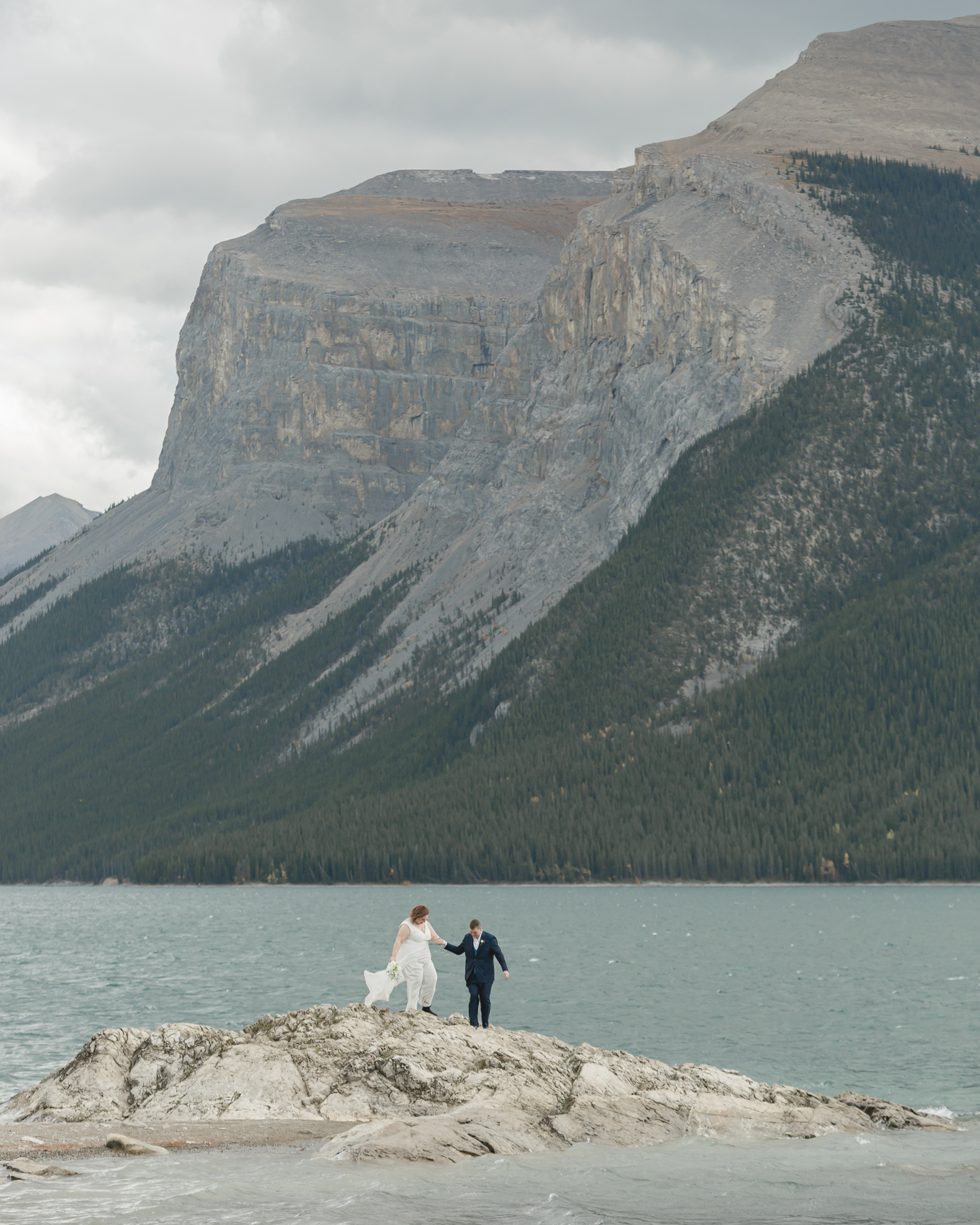 A LGBTQIA+ couple after their wedding exploring Lake Minnewanka 