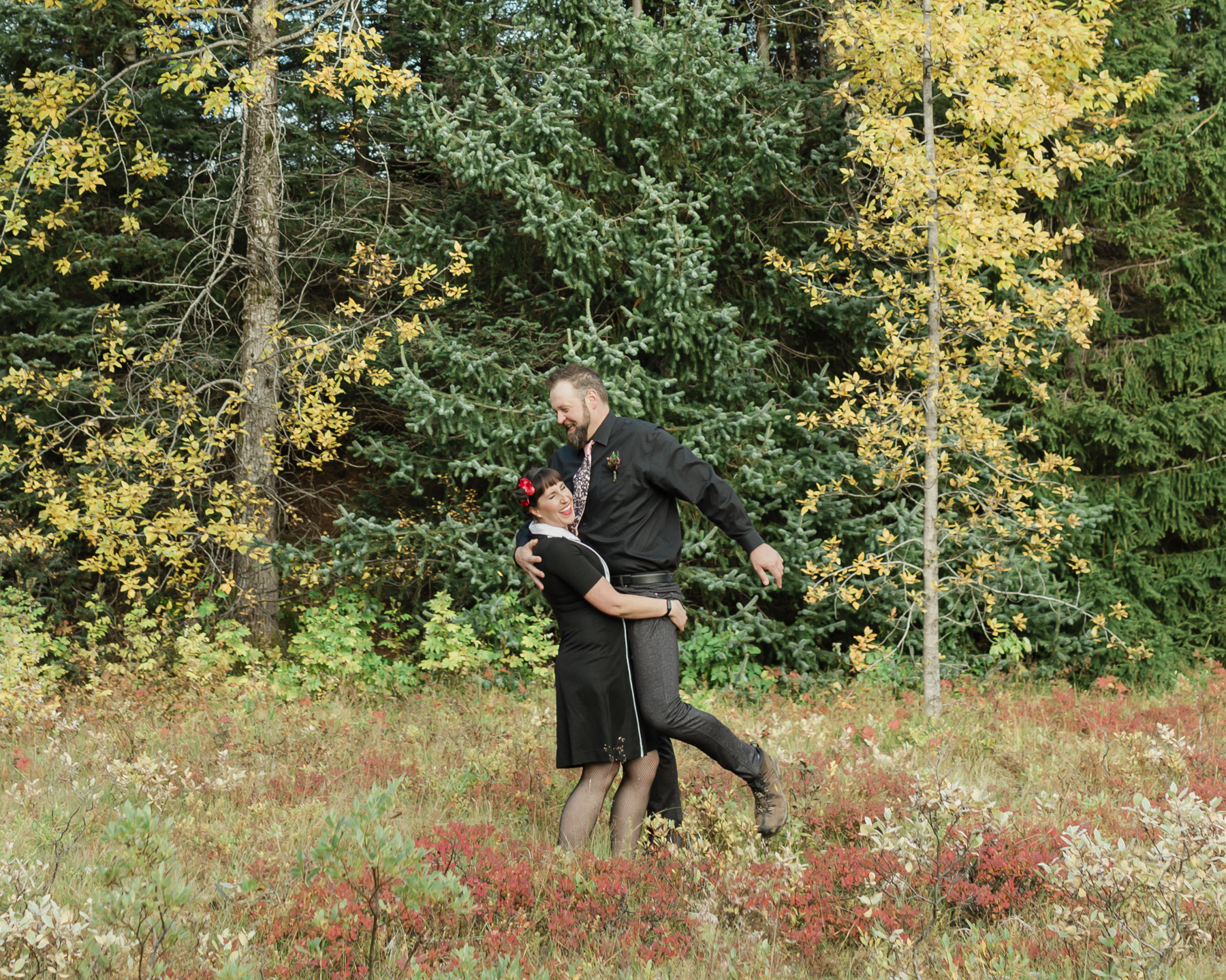 Wedding couple's portraits in the Iceland forest, the bride picked up the groom, green and yellow trees are behind them