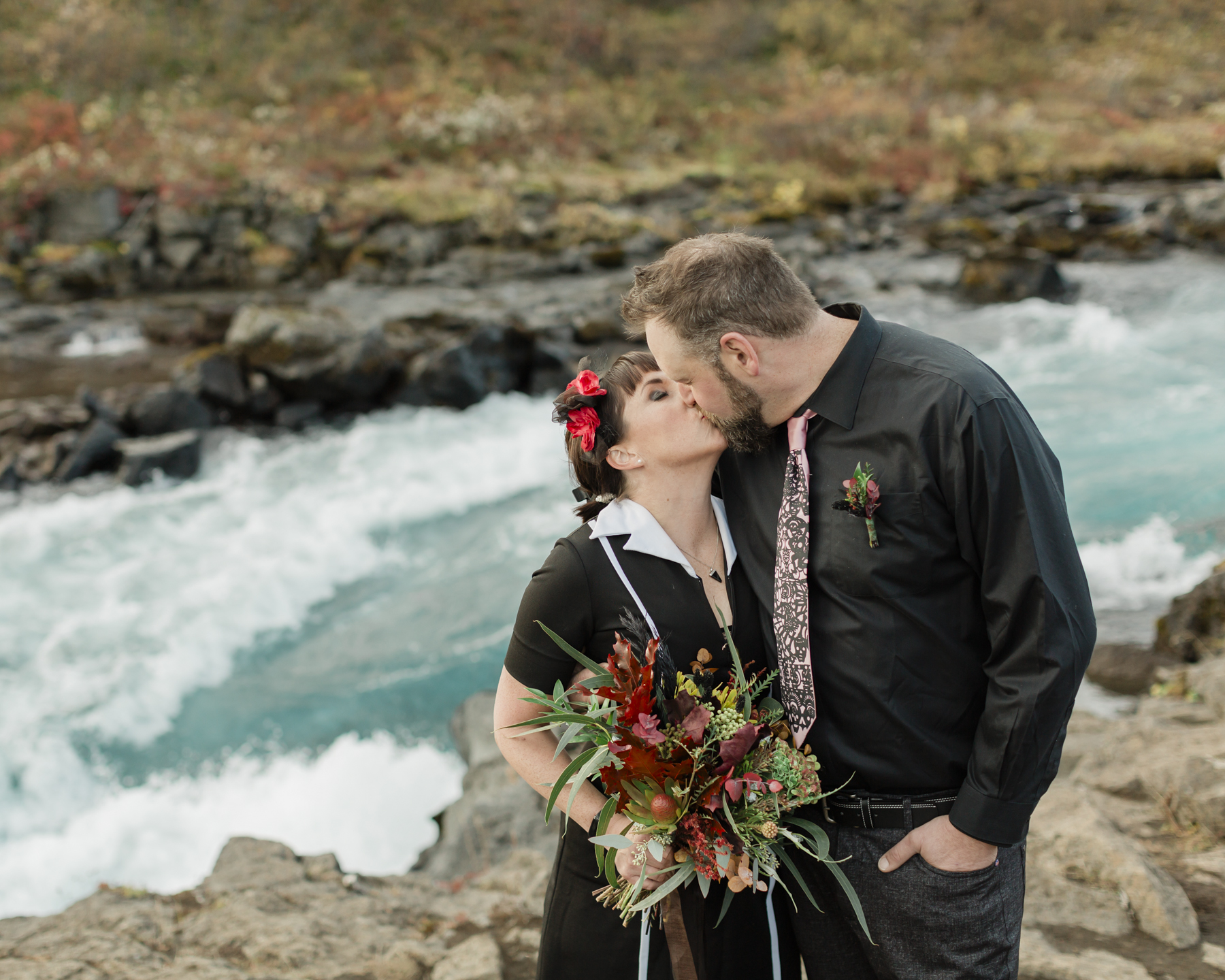 A couple that are kissing after their wedding ceremony in Iceland in front of a waterfall