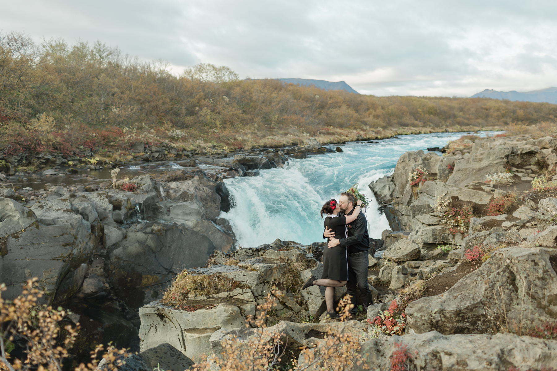 A couple that are kissing after their wedding ceremony in Iceland in front of a waterfall