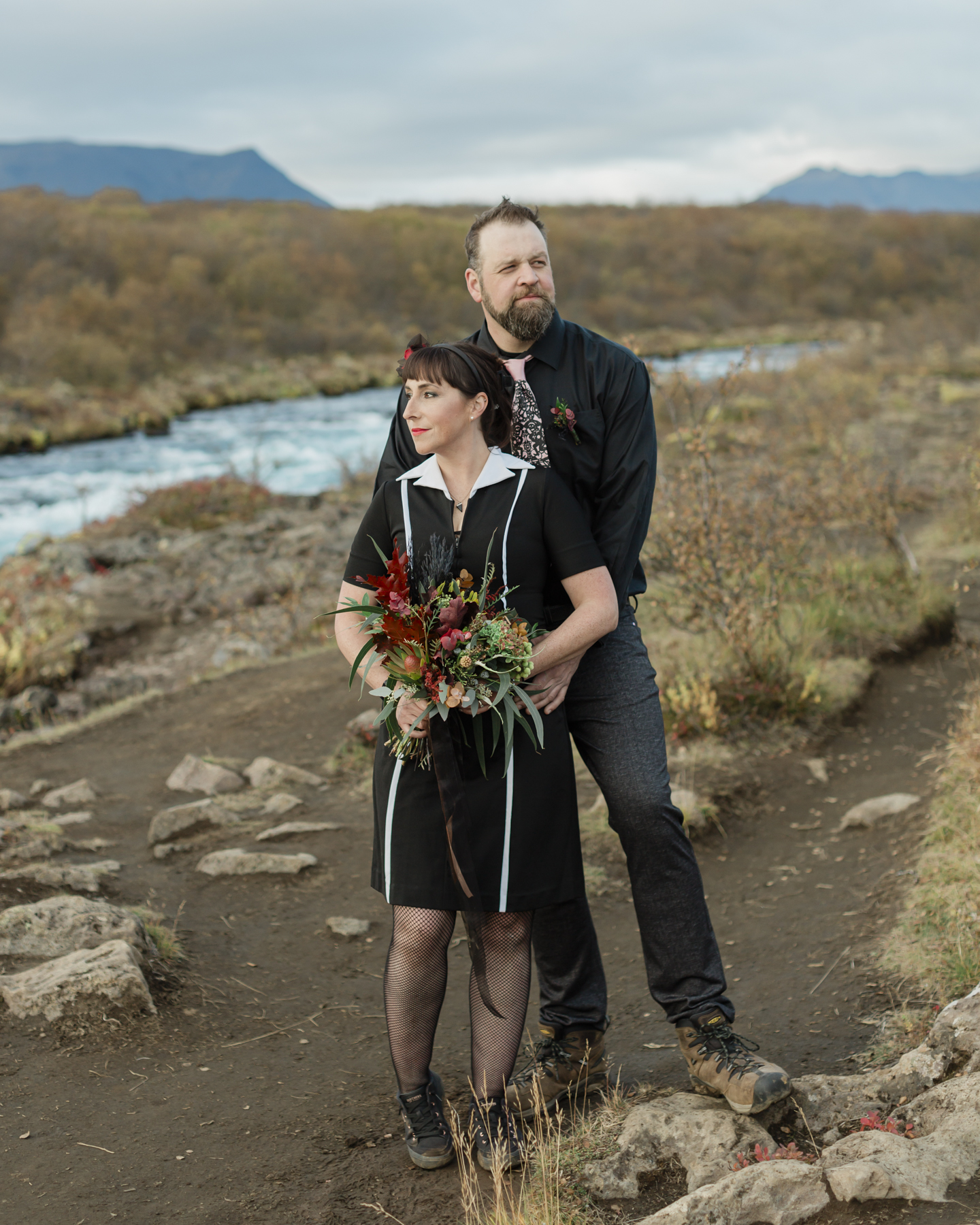 Virginia and Derek standing portrait in front of an Iceland waterfall after their wedding