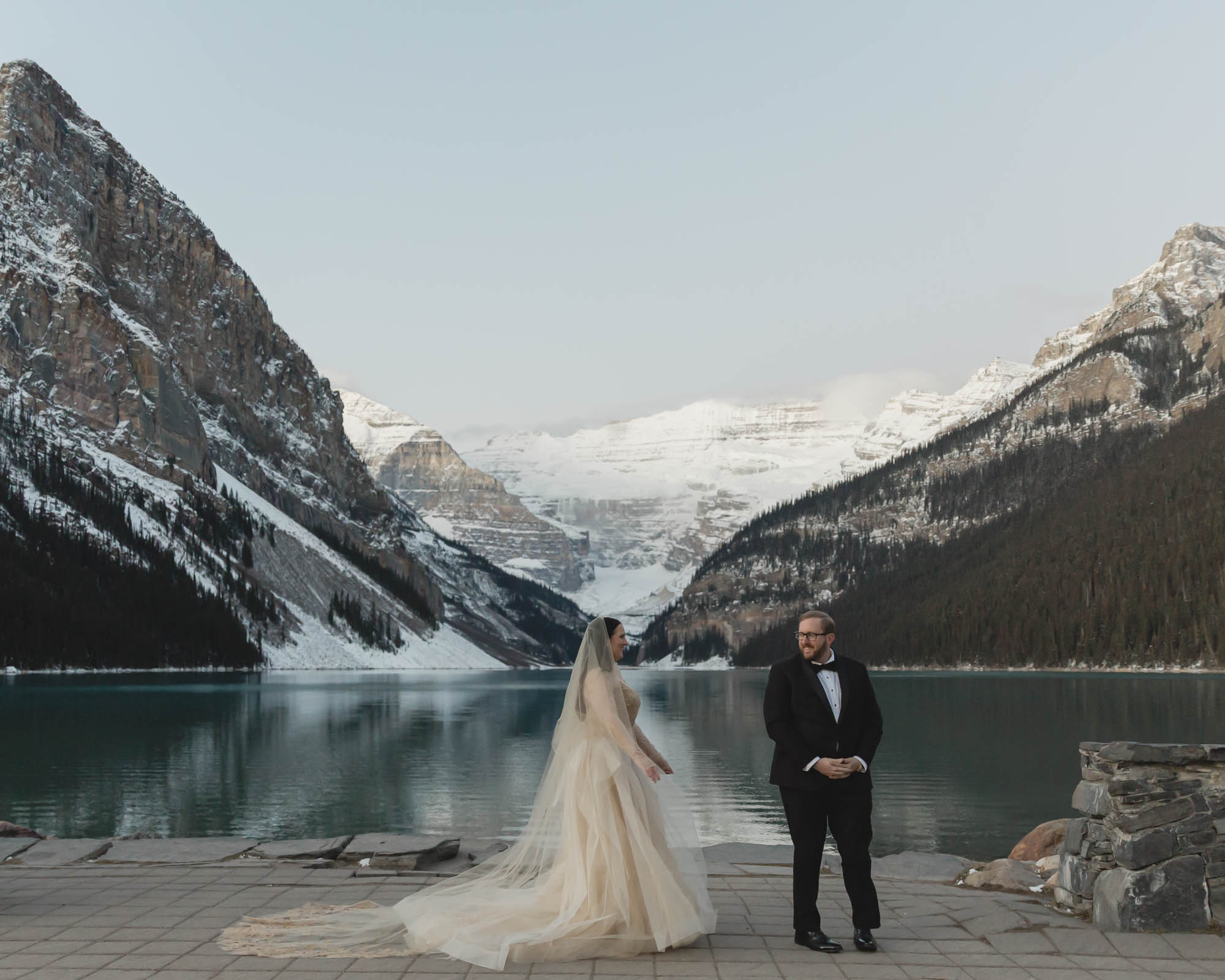 Lake Louise Elopement in Banff National Park, the couple is having their first look and the groom is turning around to see her for the first time in her wedding dress.
