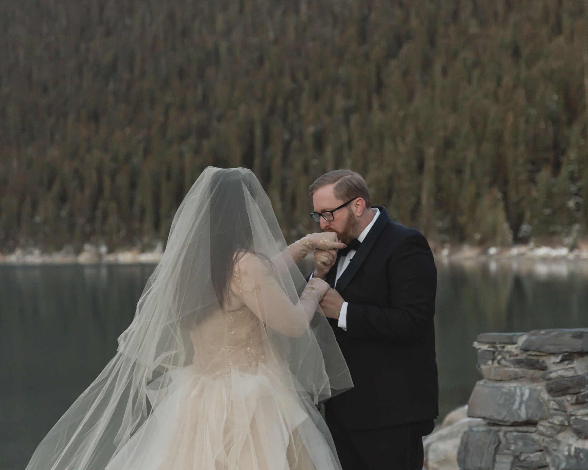 Banff National Park wedding, the groom is kissing the brides hand after their first look.
