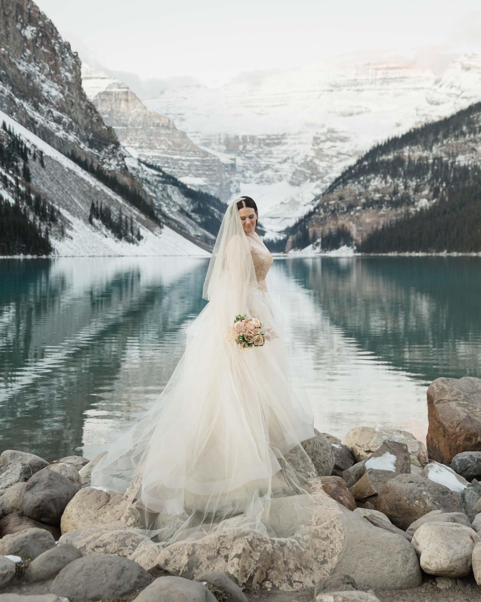 Bridal portraits in the mountains, she is looking down the back of her wedding dress
