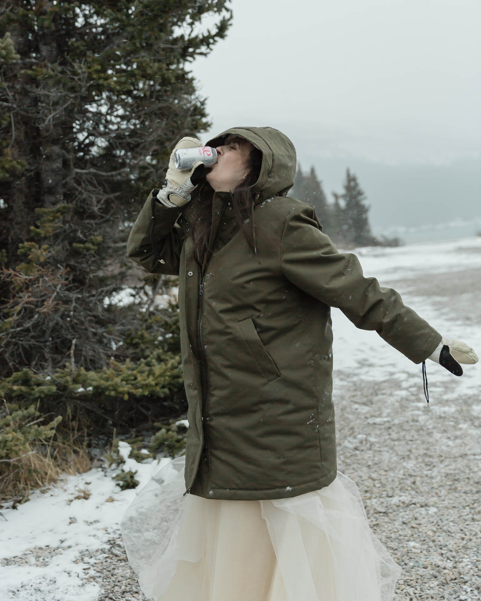 Wedding couple enjoying a winter picnic at Bow Lake in Banff National Park during their Elopement, featuring diet coke and a charcuterie board