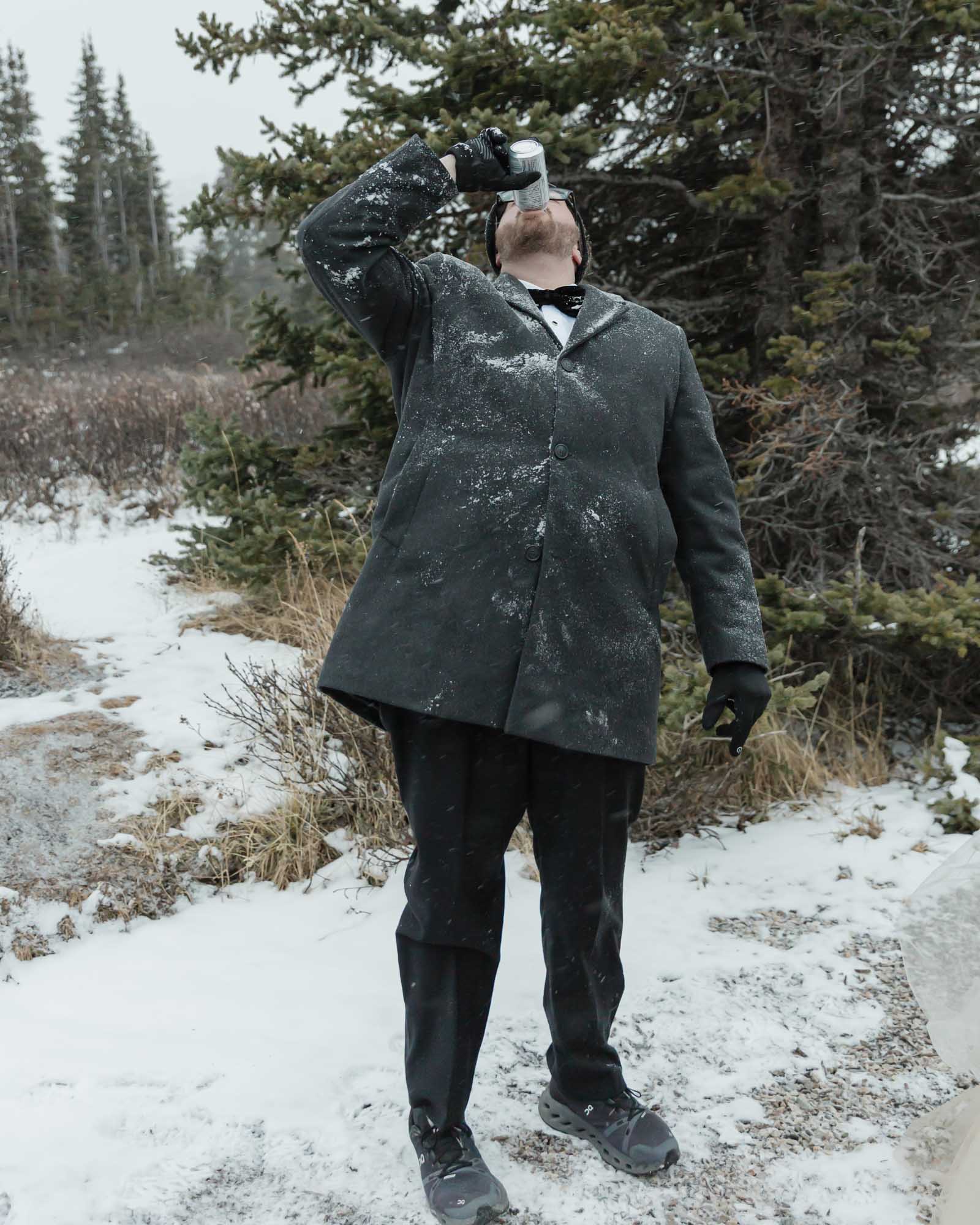 Wedding couple enjoying a winter picnic at Bow Lake in Banff National Park during their Elopement, featuring diet coke and a charcuterie board