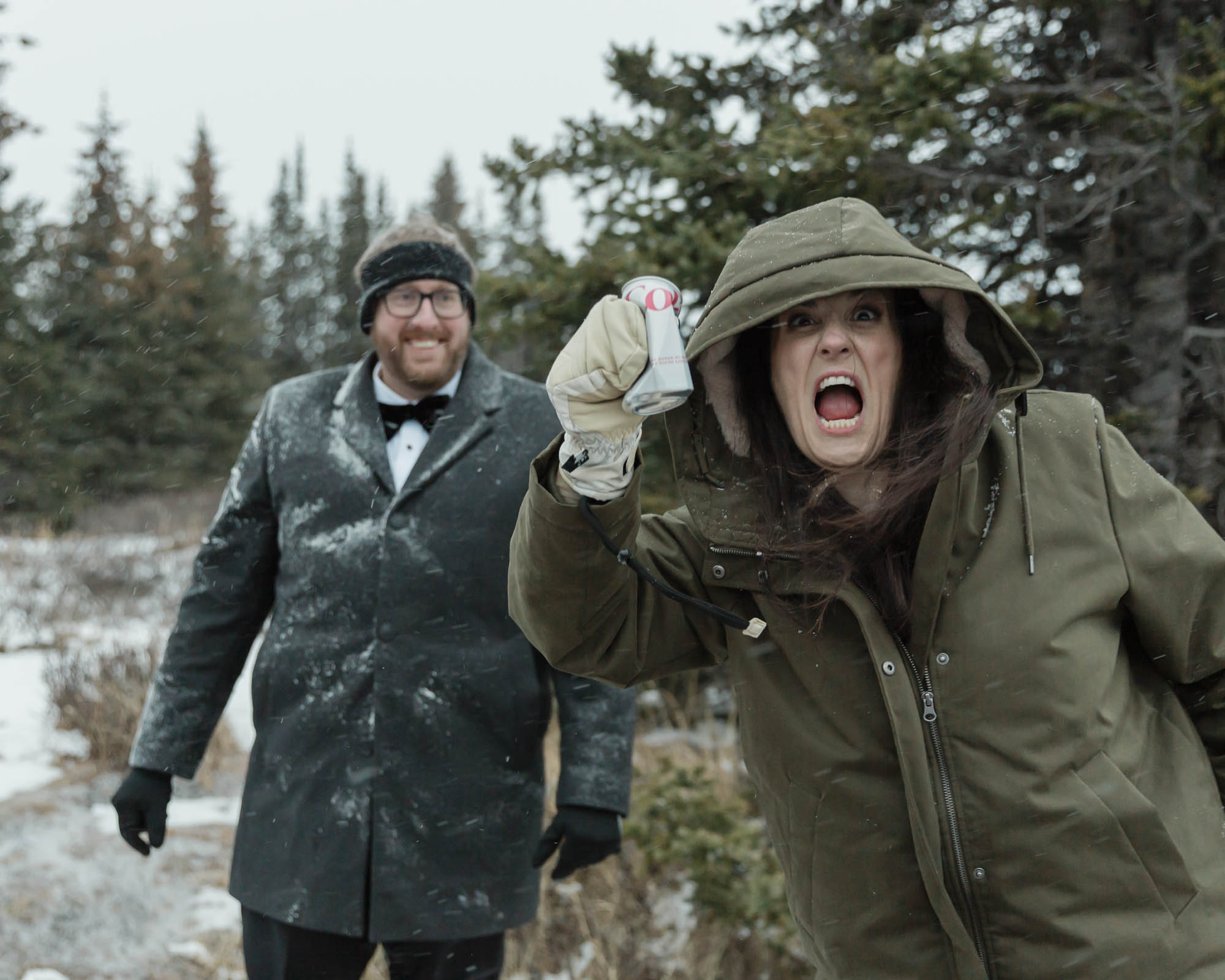 Wedding couple enjoying a winter picnic at Bow Lake in Banff National Park during their Elopement, featuring diet coke and a charcuterie board