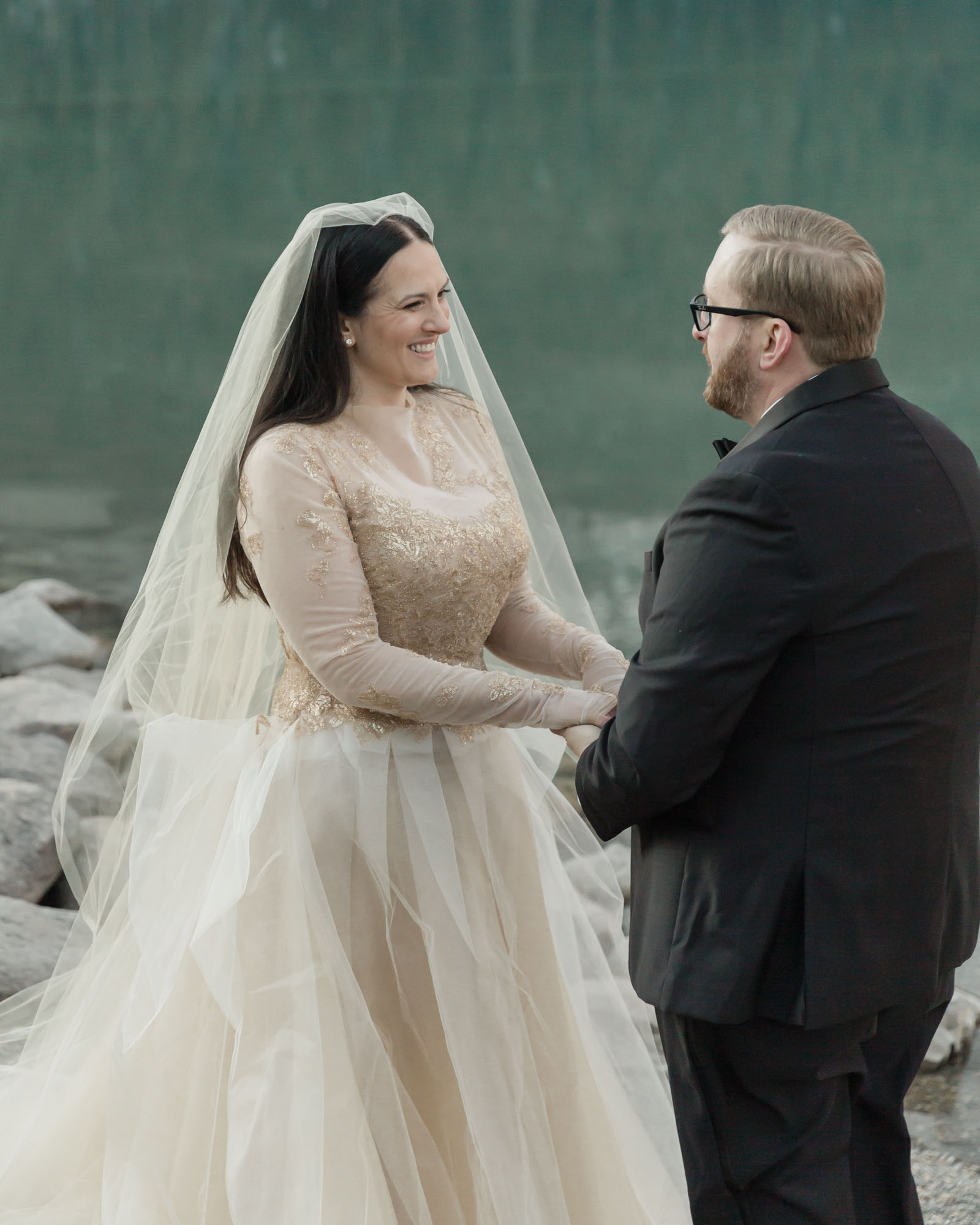 Banff National Park wedding, the couple is looking at each other during their vows and the bride is smiling