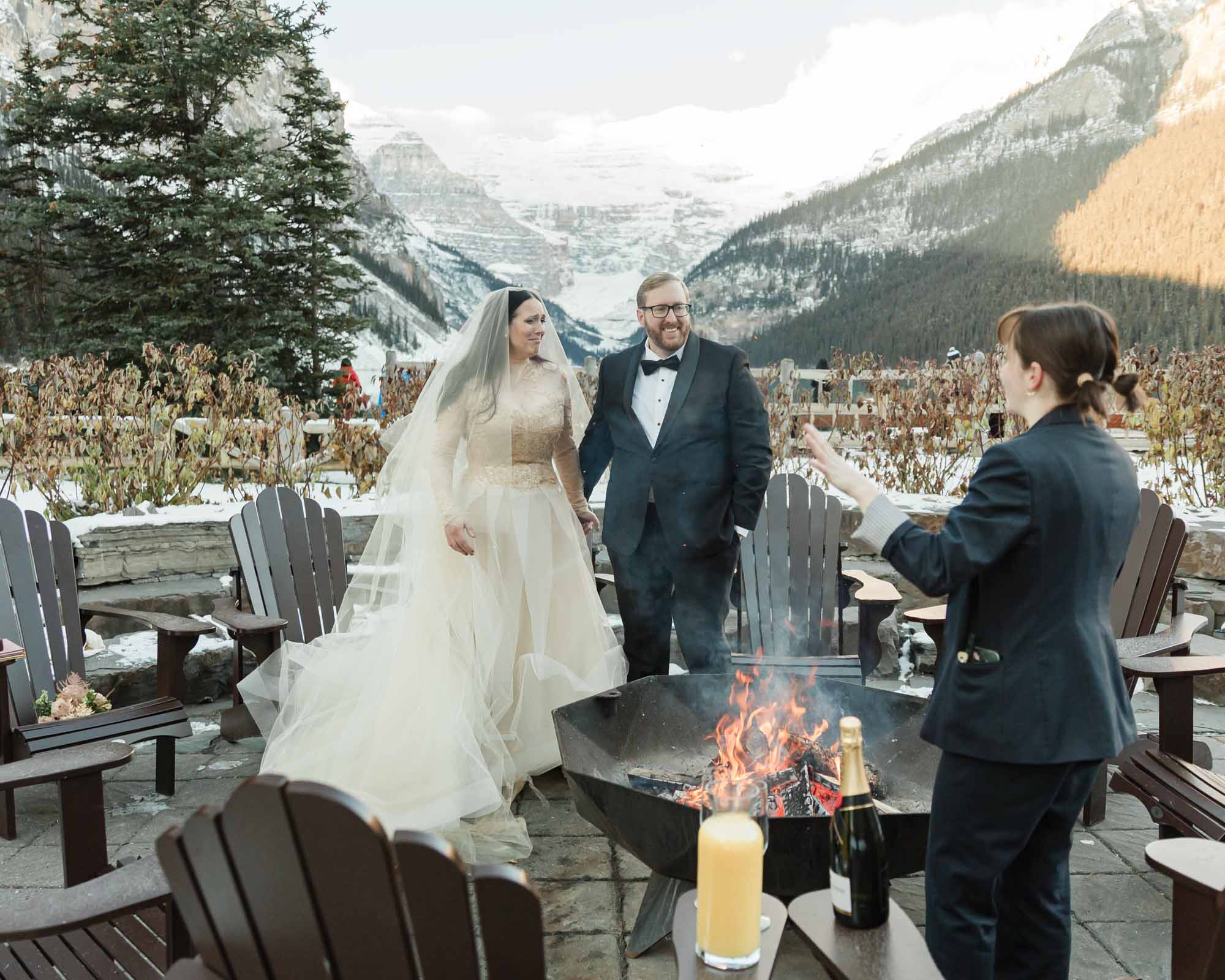 A couple is enjoying a bonfire in front of the Fairmont Chateau Lake Louise after their ceremony at sunrise