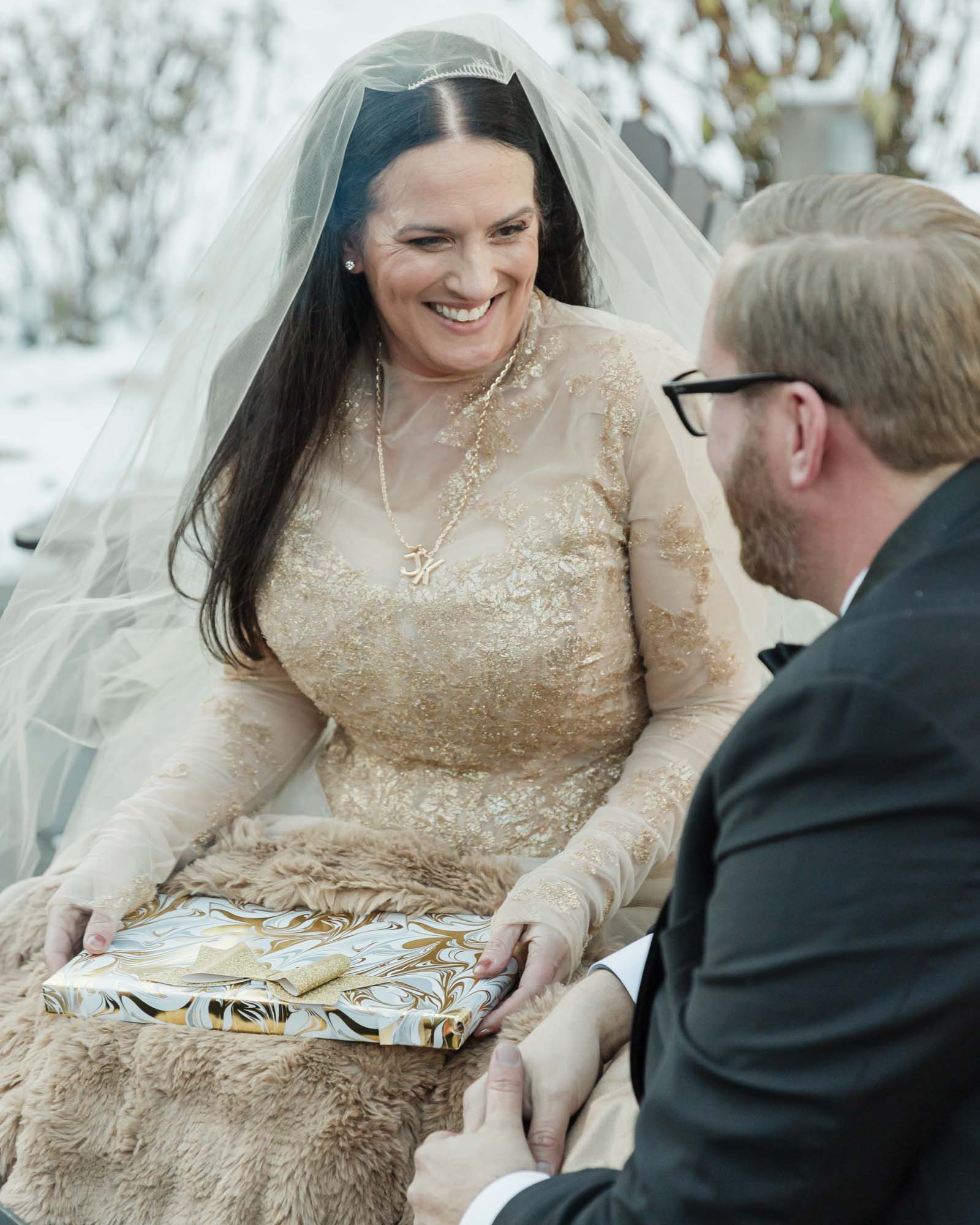 A couple is exchanging gifts and enjoying a bonfire in front of the Fairmont Chateau Lake Louise after their wedding ceremony at sunrise