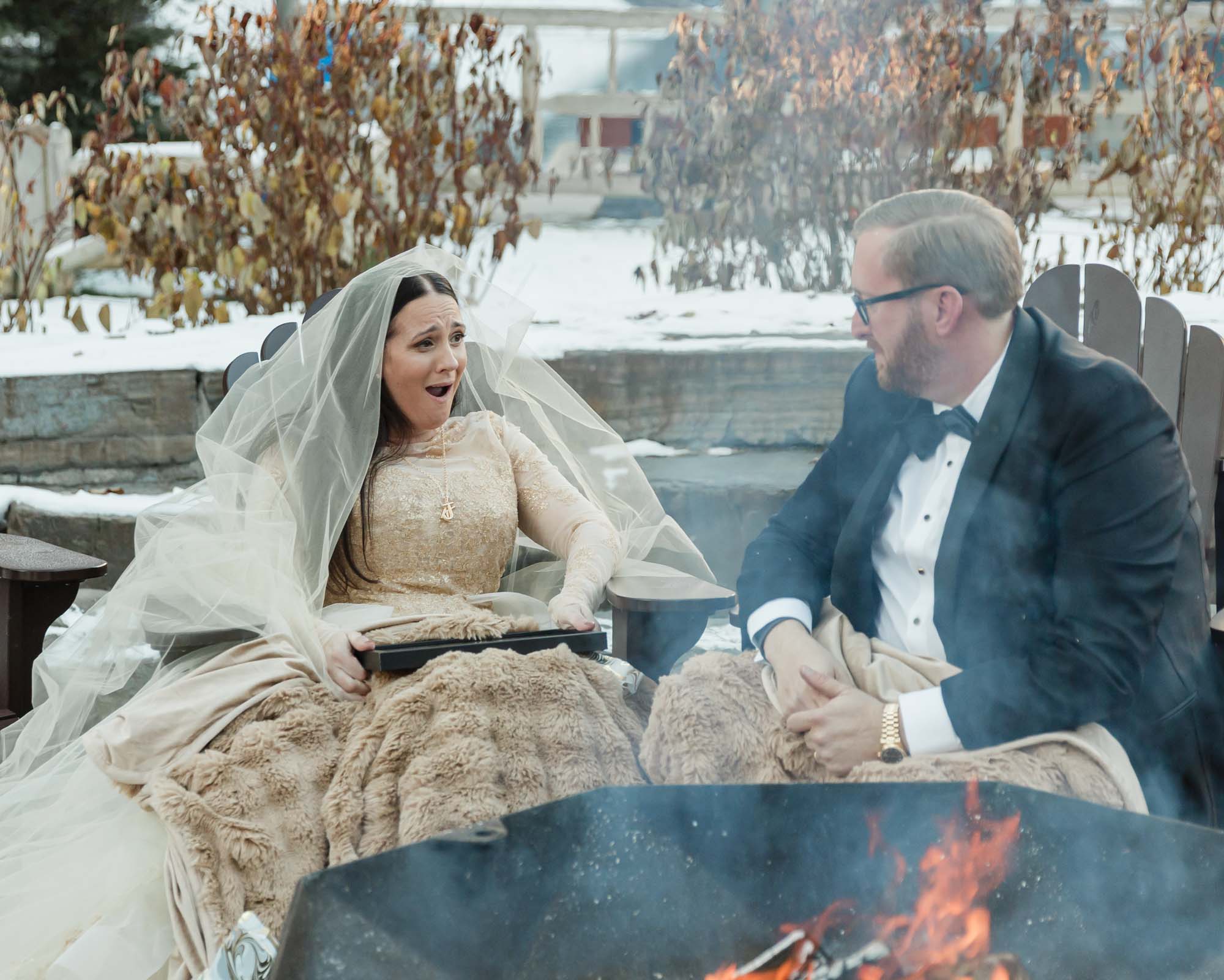 A couple is exchanging gifts and enjoying a bonfire in front of the Fairmont Chateau Lake Louise after their wedding ceremony at sunrise