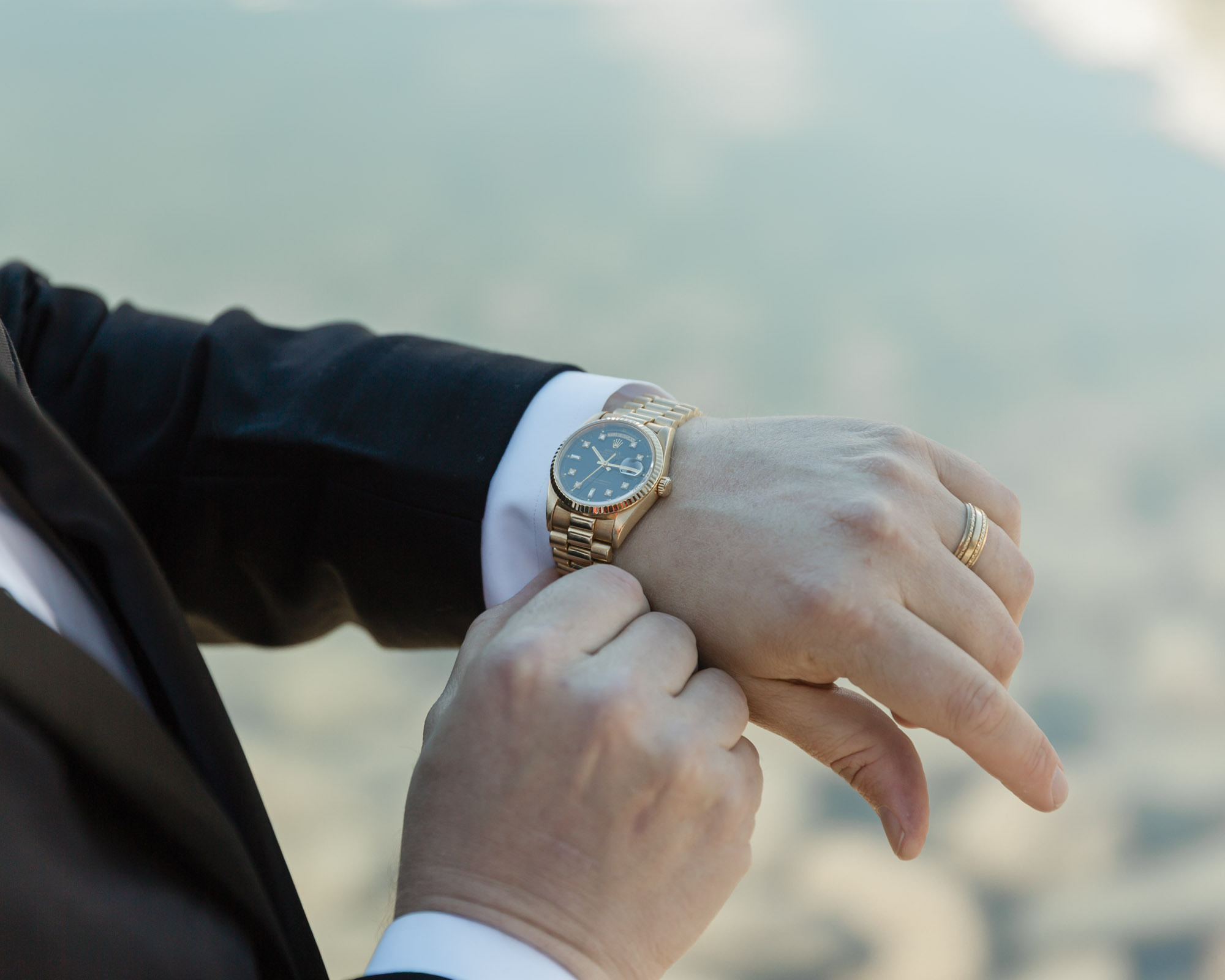 Groom portraits in front of the blue alpine waters for their mountain elopement with his watch accessory in focus