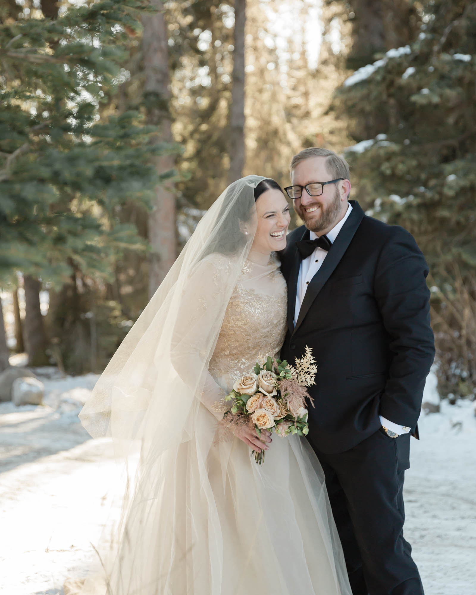 Wedding portraits in the forest in Banff National Park while the couple laughs together