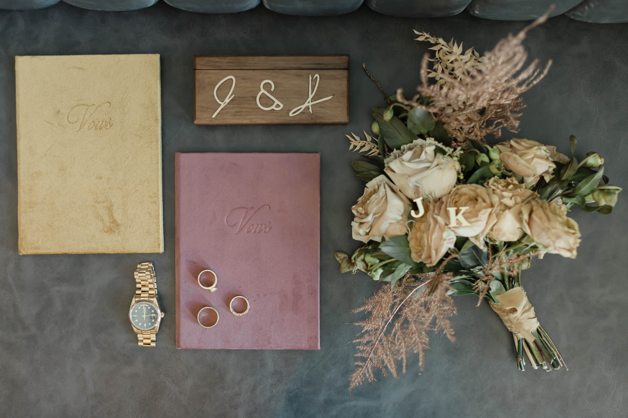 Vow books, wedding rings, bridal bouquet, cufflinks, ring box and the groom's watch featured together for an accessory and detail photo