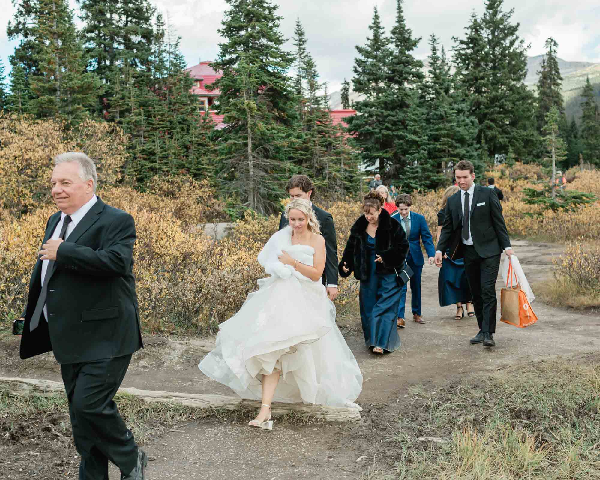 all guests and the bride and groom walking towards their ceremony location at Bow lake in banff national park 