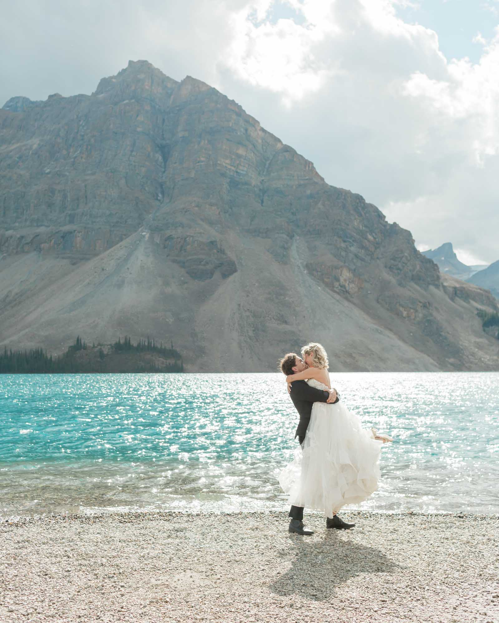 the couple hugging and spinning in front of the mountain after their wedding
