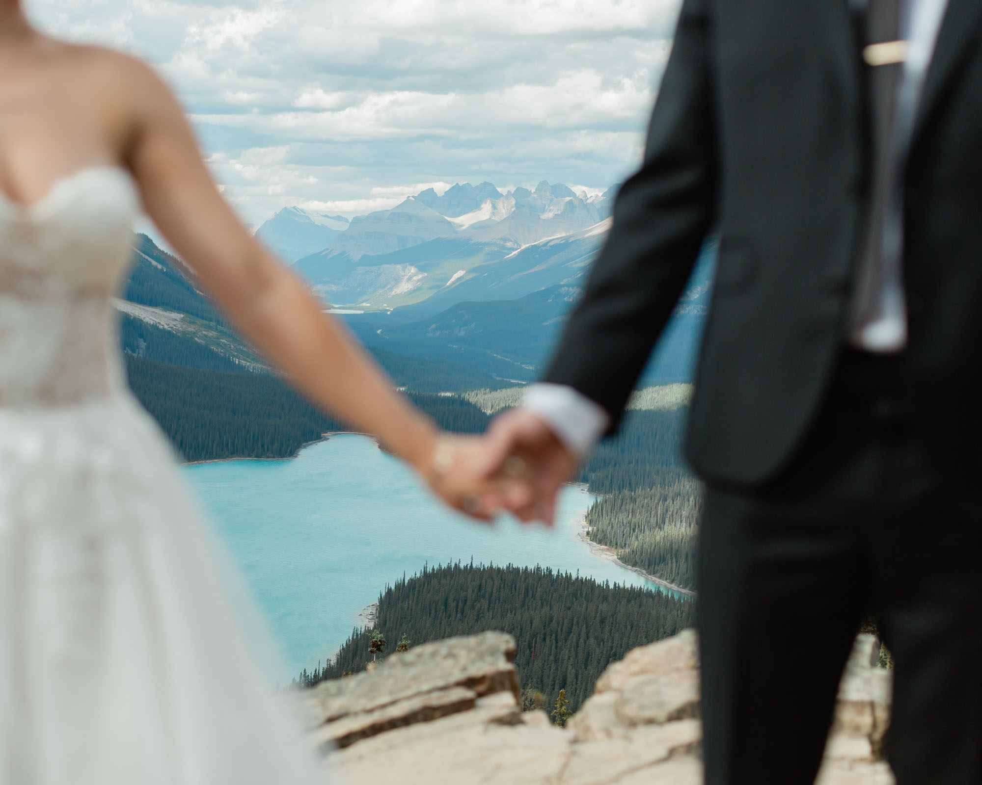 peyto lake in focus as the couple holds hands after their banff wedding