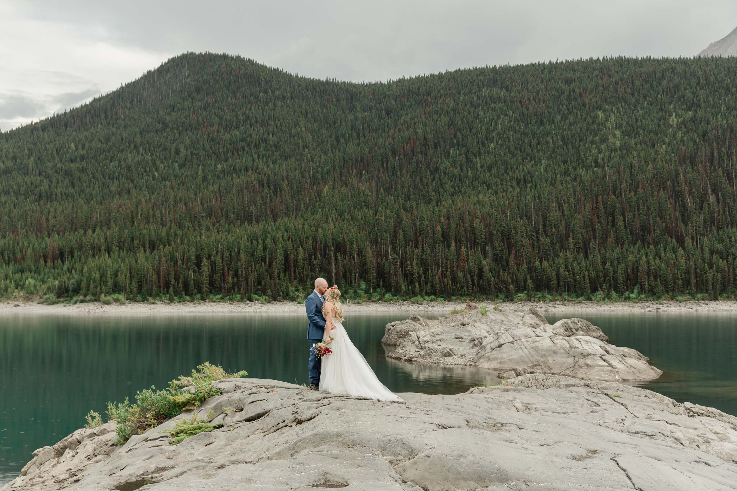 the couple kissing on an epic canadian shield rock for their Banff wedding day