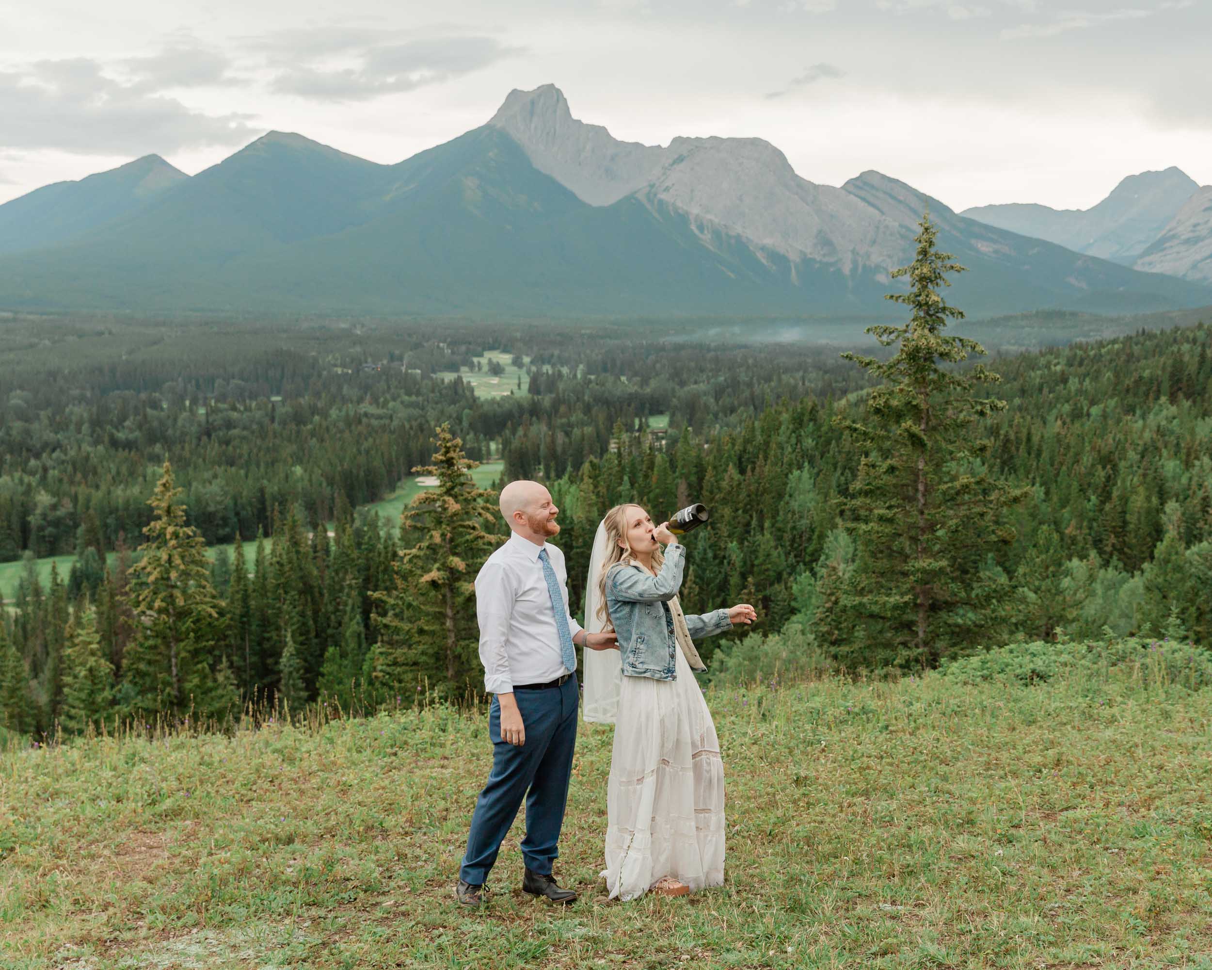 the couple celebrating after their ceremony with a champagne pop during their mountain wedding near banff