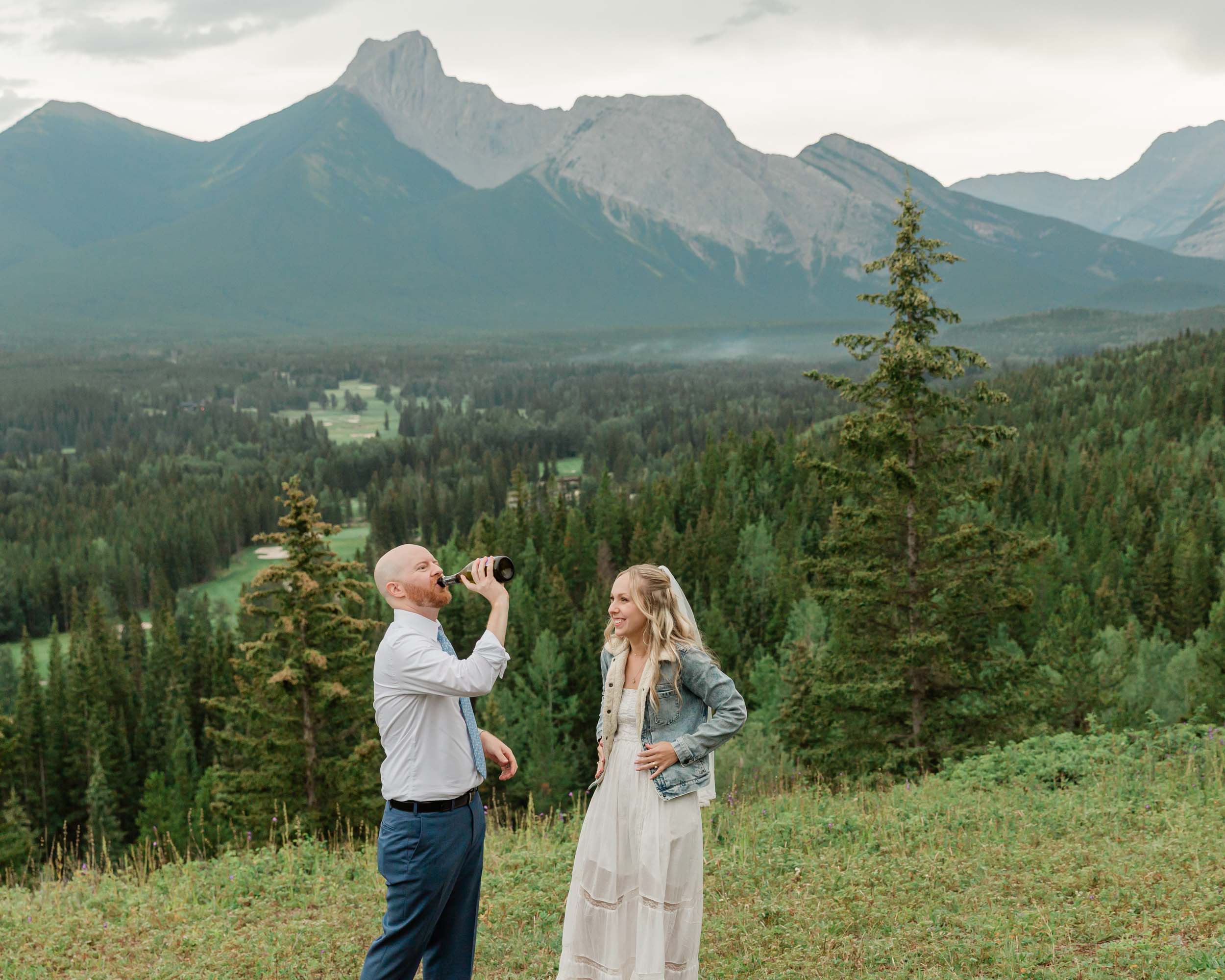 the couple celebrating after their ceremony with a champagne pop during their mountain wedding near banff