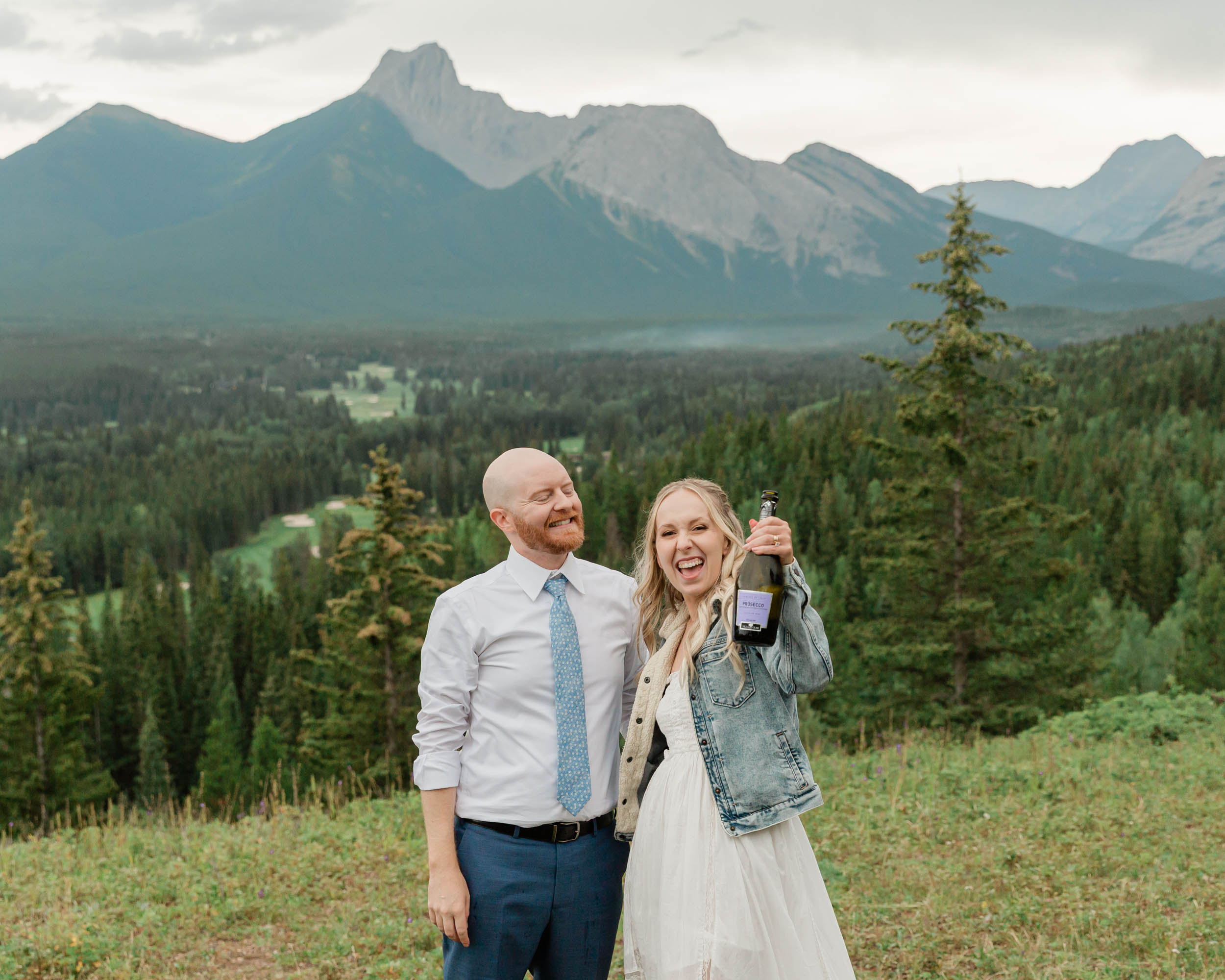 the couple celebrating after their ceremony with a champagne pop during their mountain wedding near banff