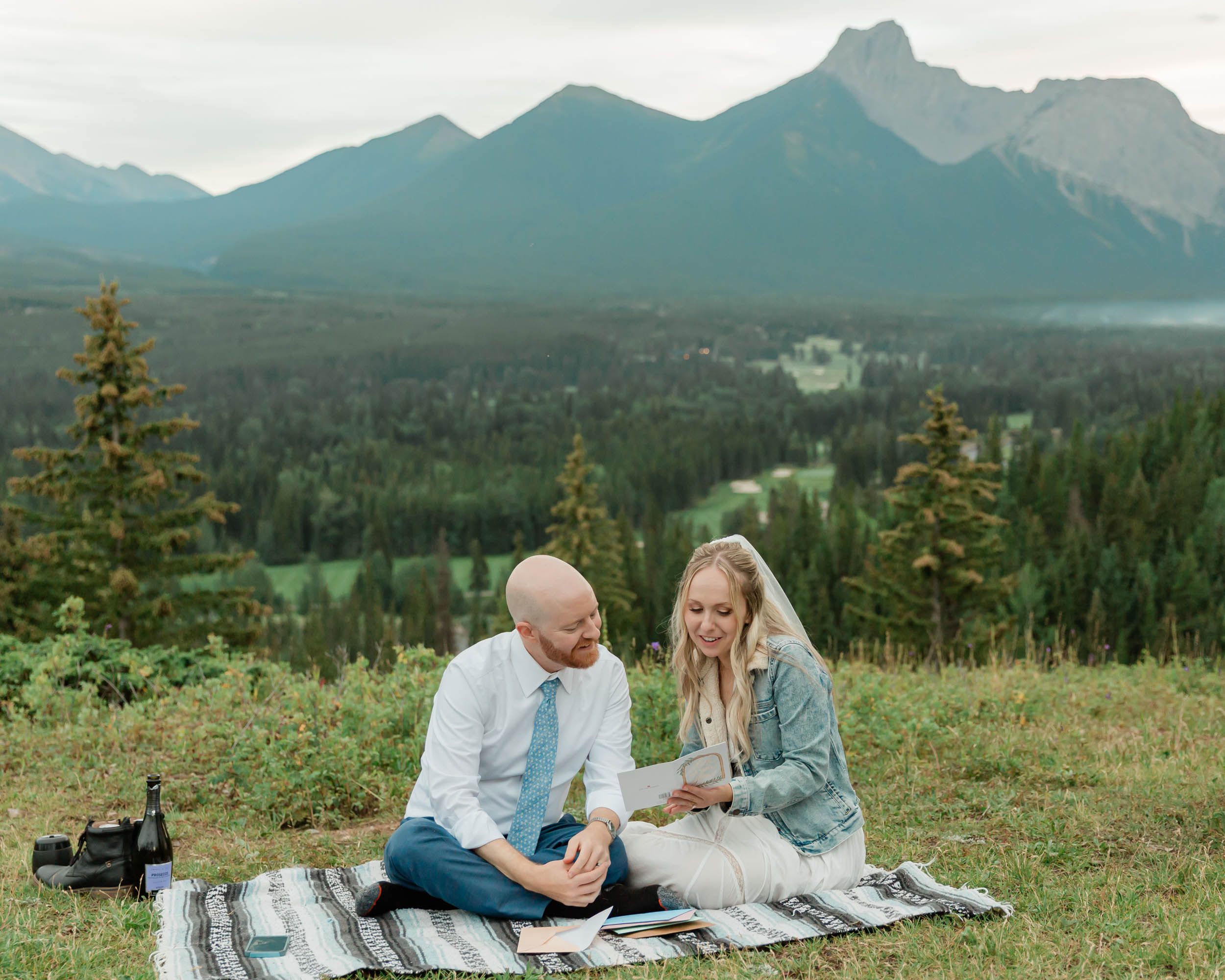 reading letters together, laughing and smiling during their mountain wedding near banff