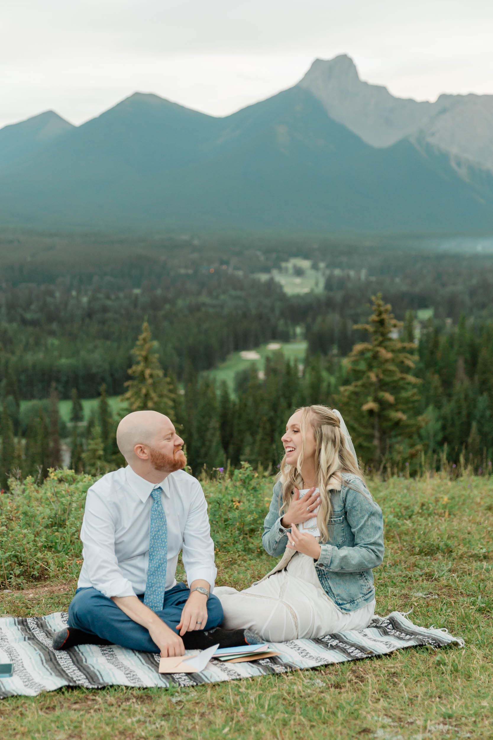 reading letters together, laughing and smiling during their mountain wedding near banff