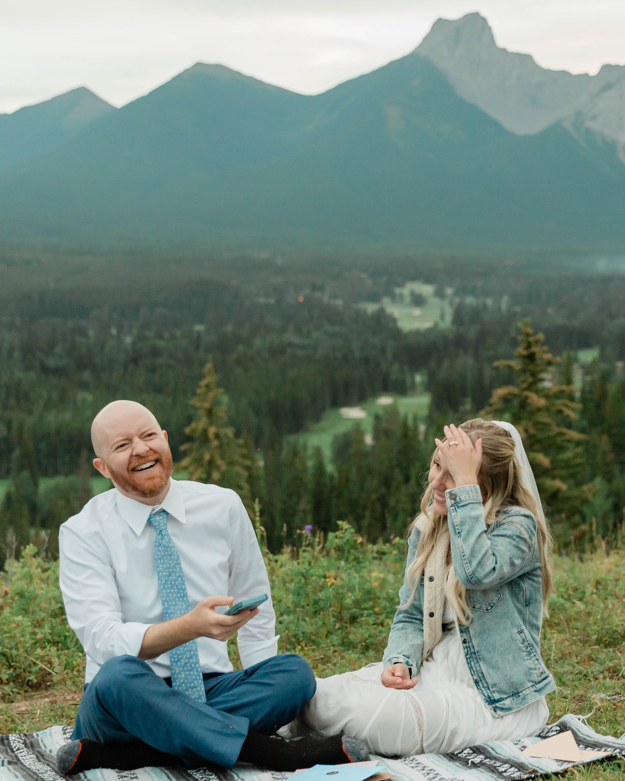 reading letters together, laughing and smiling during their mountain wedding near banff