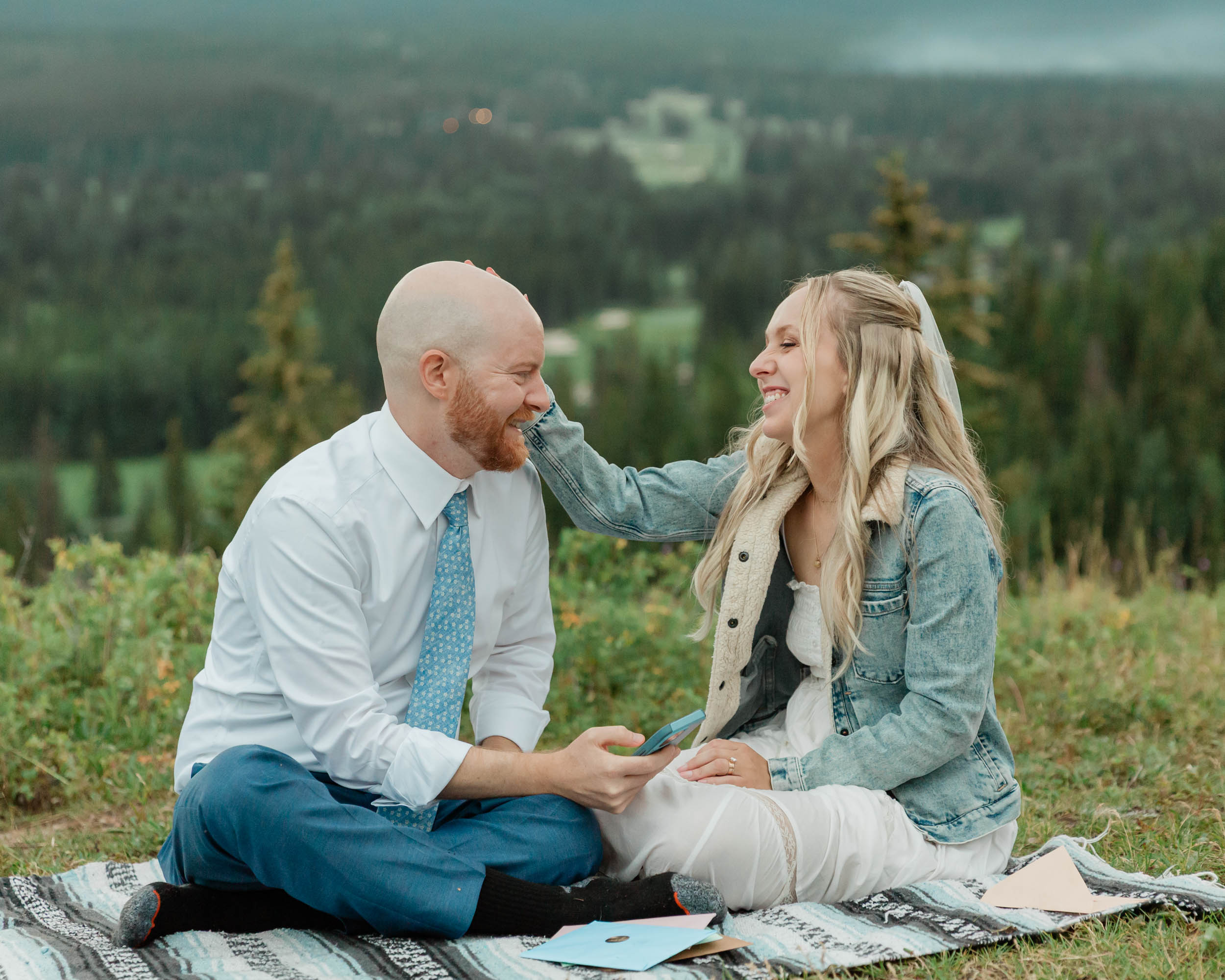 reading letters together, laughing and smiling during their mountain wedding near banff