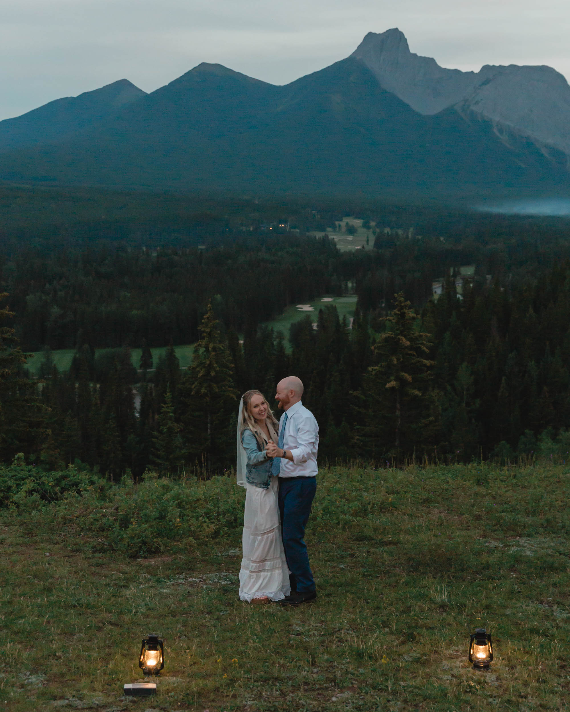 megan and scott embracing during their night time first dance with the banff mountain range behind them for their elopement day