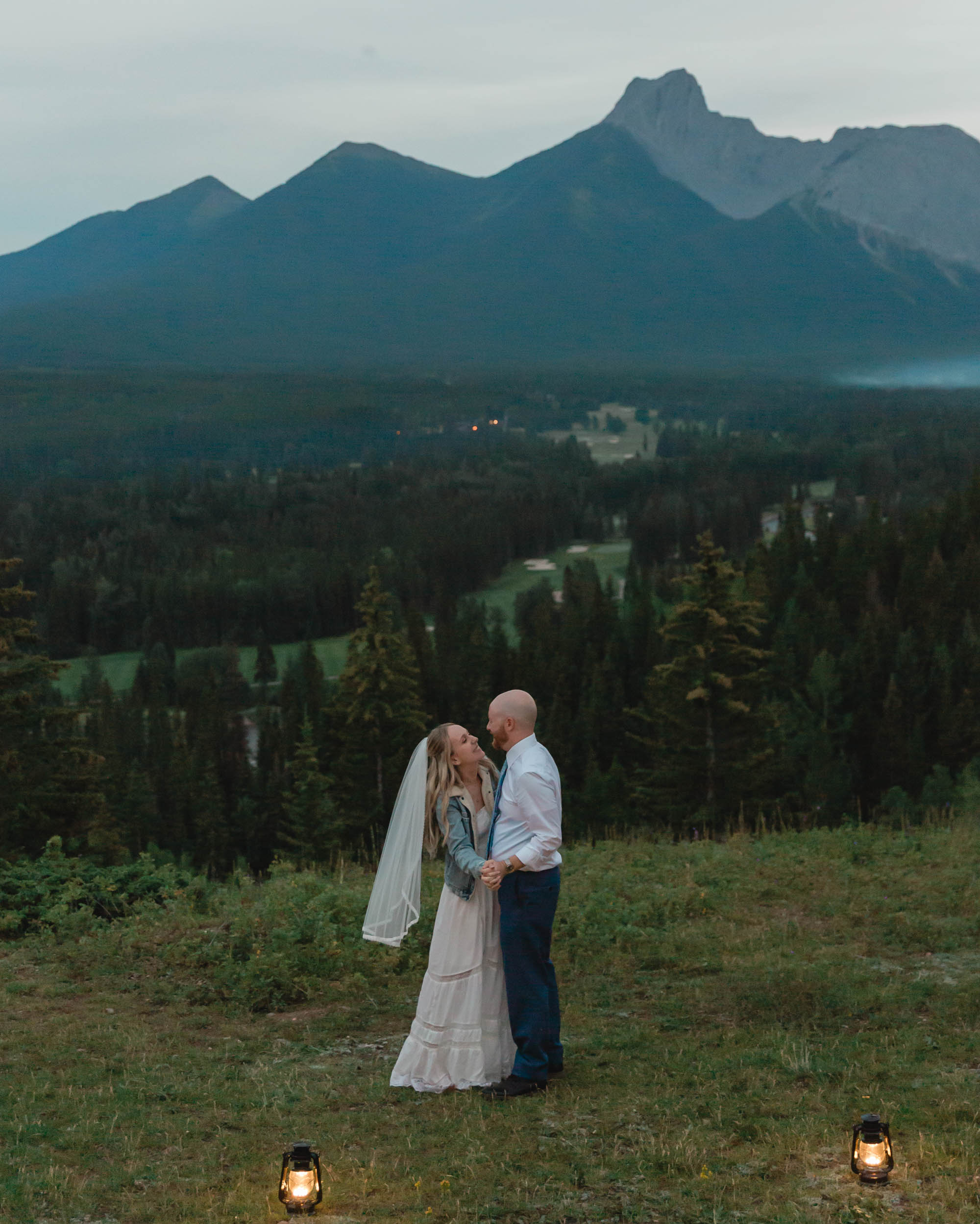 megan and scott embracing during their night time first dance with the banff mountain range behind them for their elopement day
