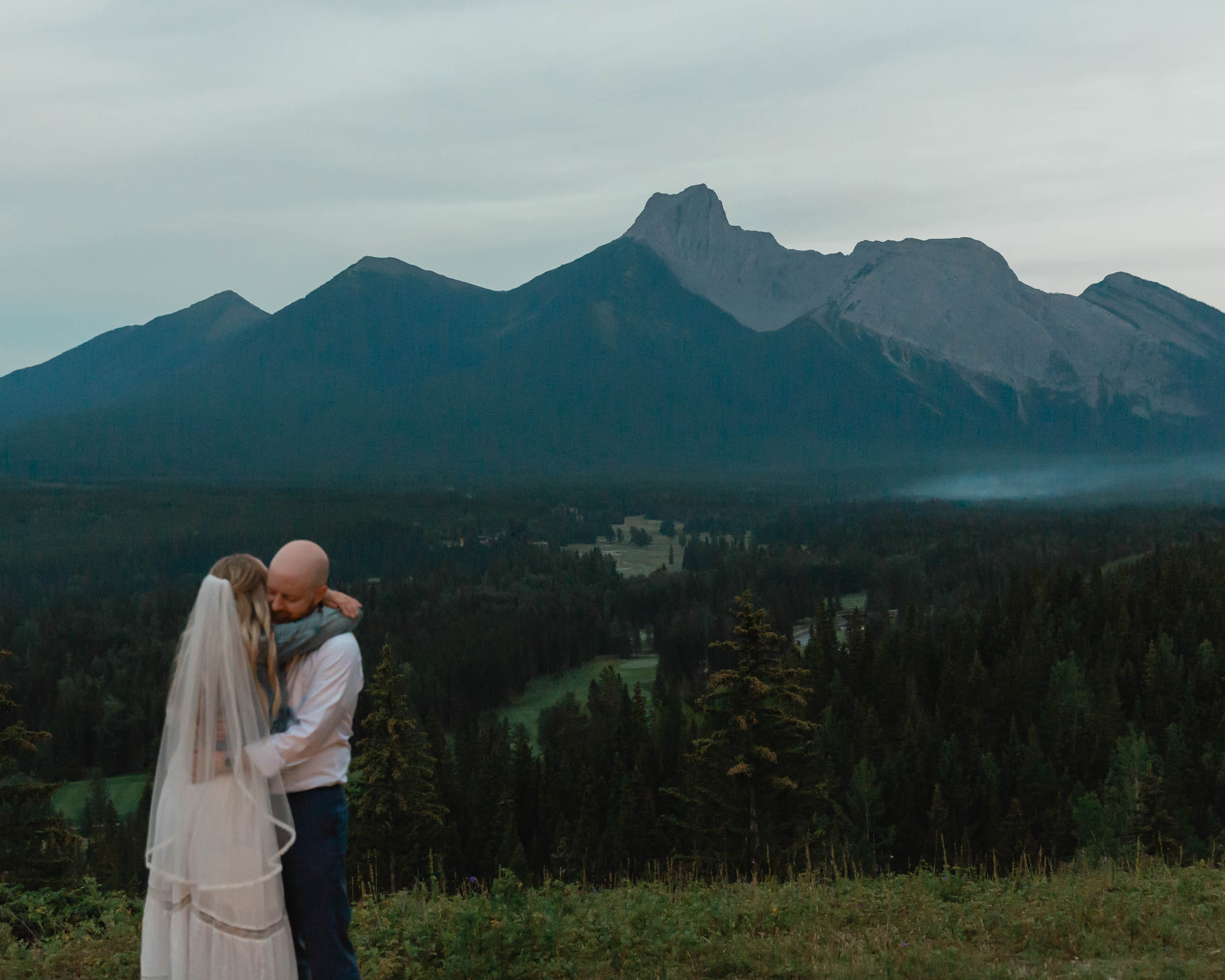 megan and scott embracing during their first dance with the banff mountain range behind them for their elopement day