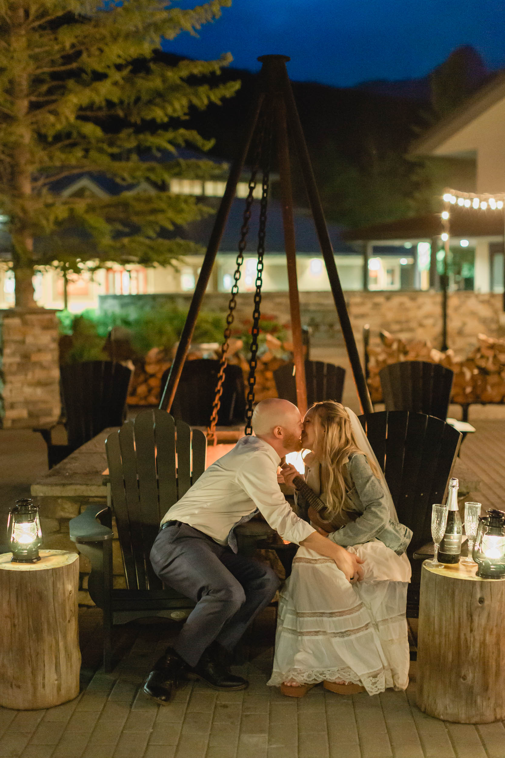 couple celebrating after their mountain elopement with champagne and smores in front of a bonfire