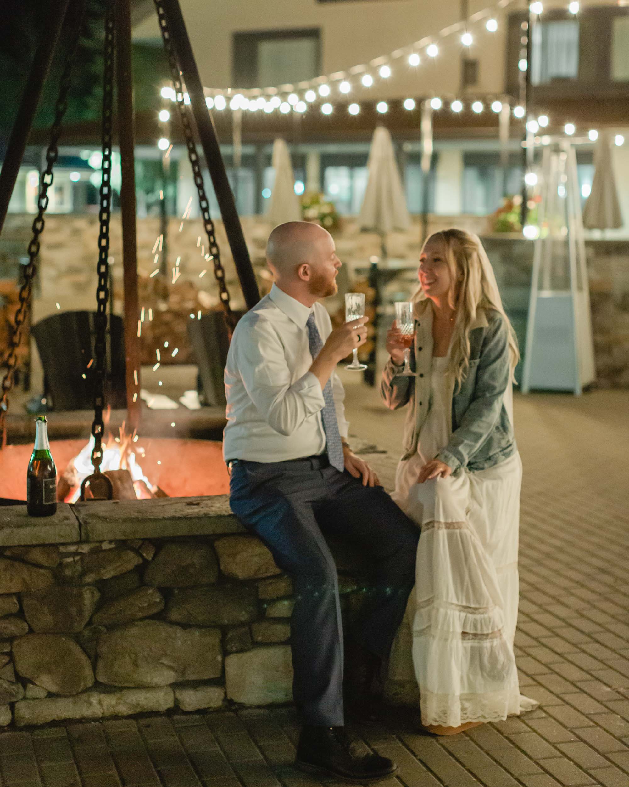 couple celebrating after their mountain elopement with champagne and smores in front of a bonfire