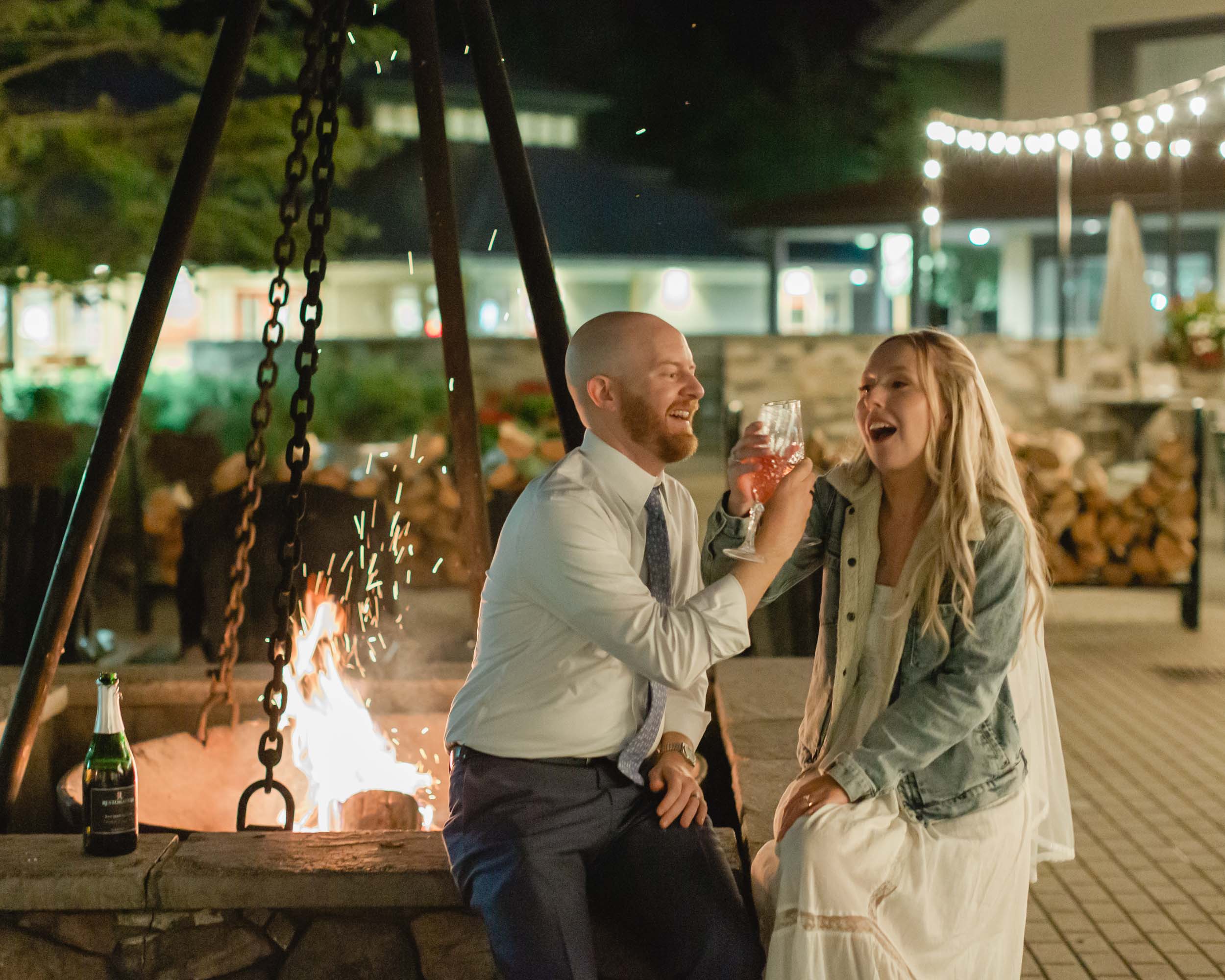 couple celebrating after their mountain elopement with champagne and smores in front of a bonfire