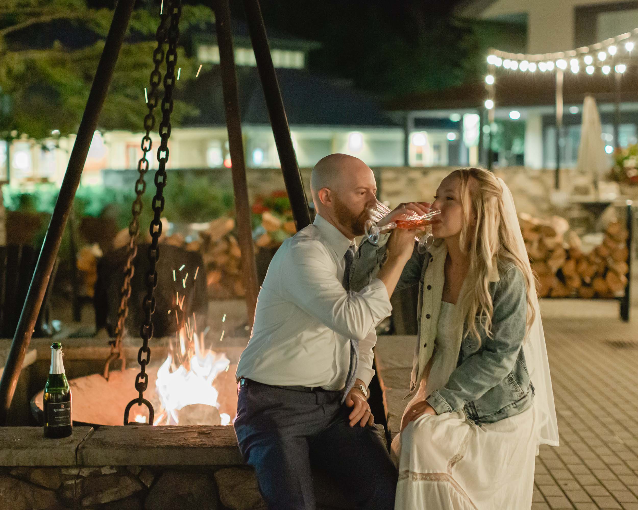 couple celebrating after their mountain elopement with champagne and smores in front of a bonfire