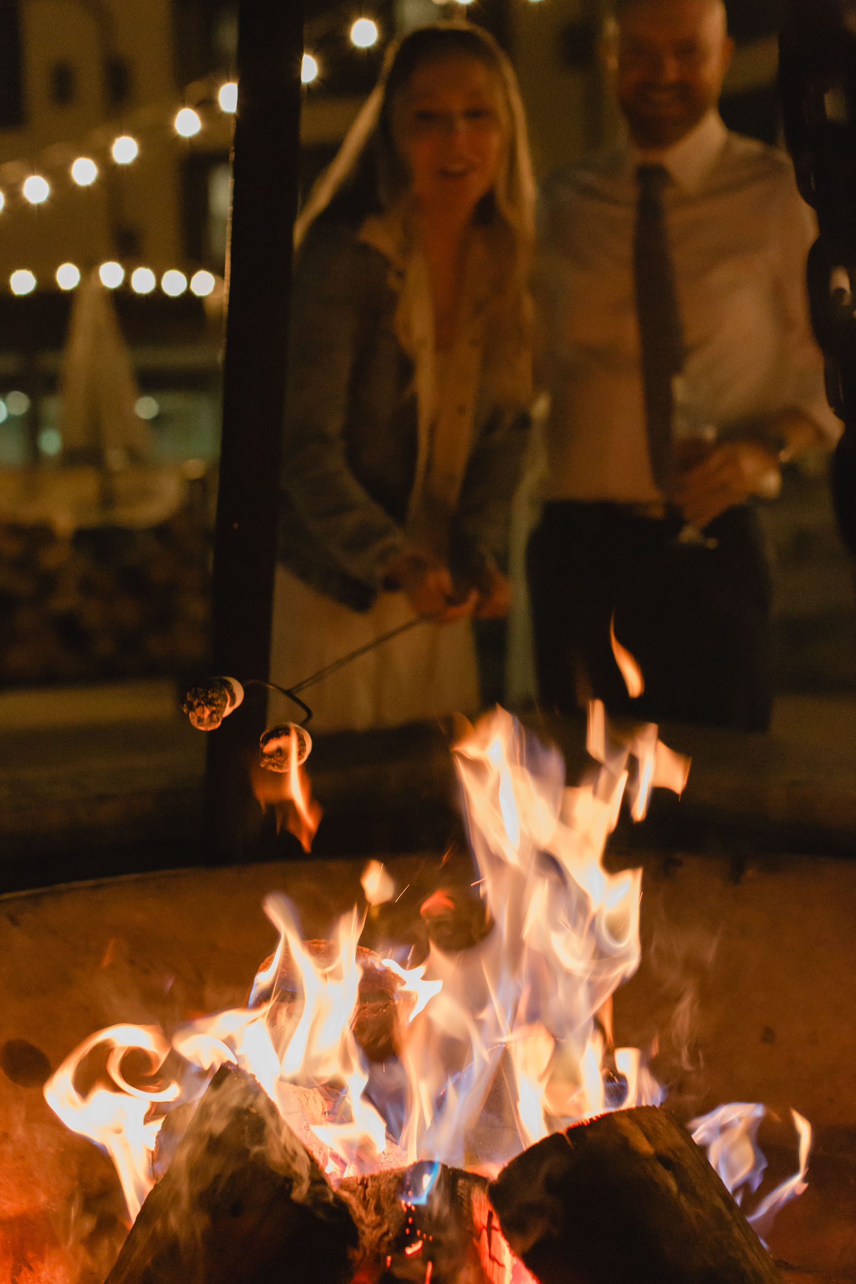 couple celebrating after their mountain elopement with champagne and smores in front of a bonfire