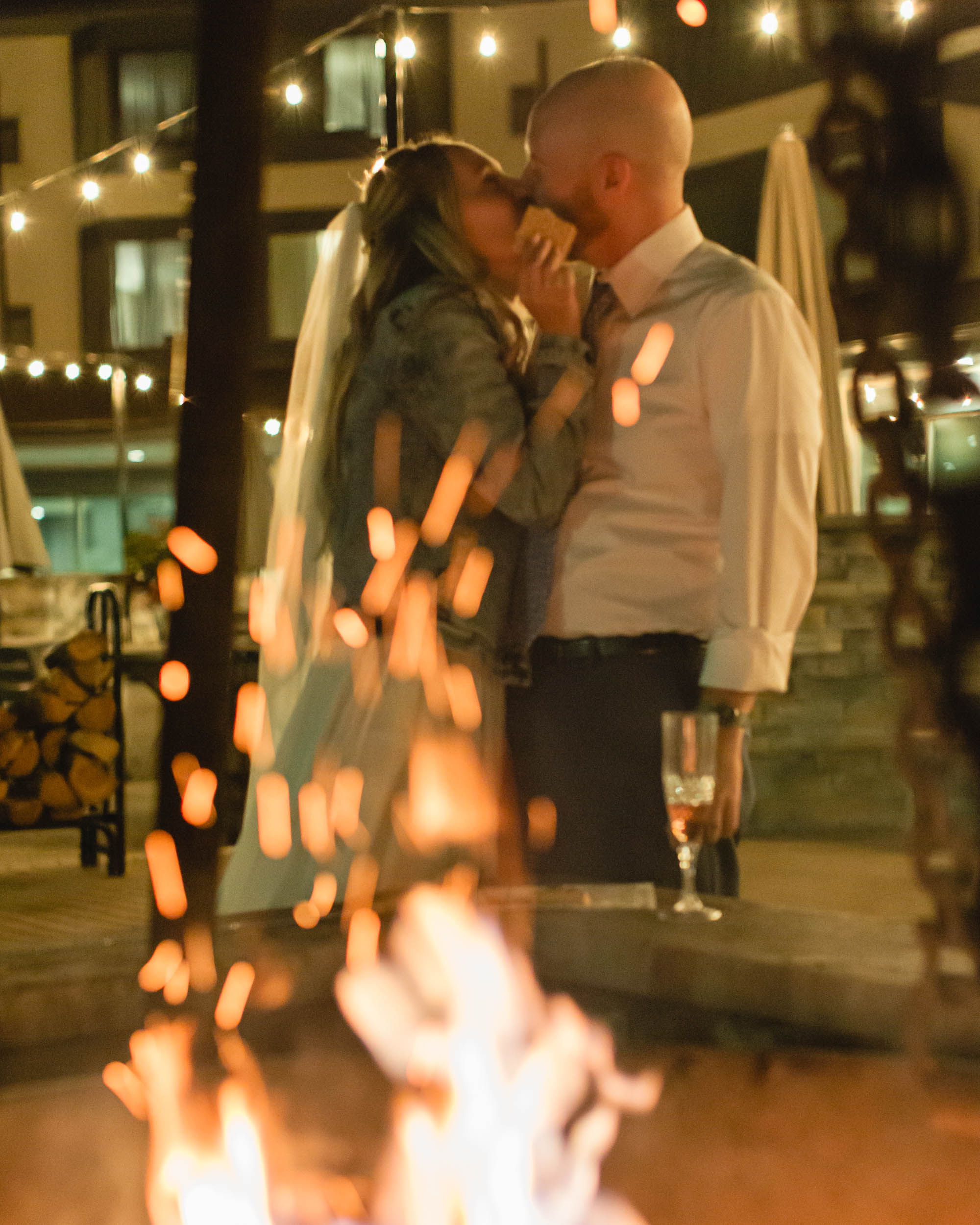 couple celebrating after their mountain elopement with champagne and smores in front of a bonfire