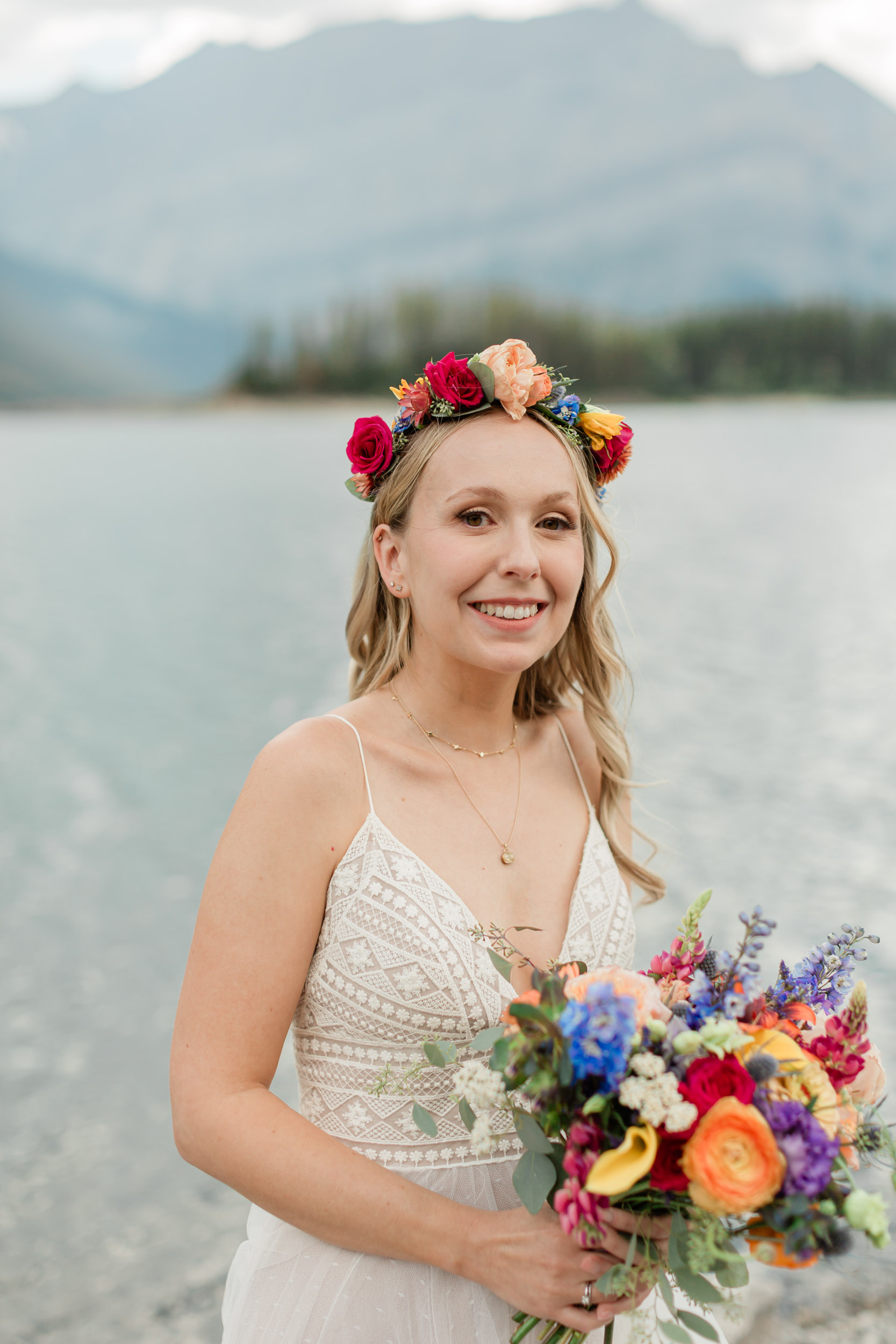 the bride is laughing smiling during her portrait in front of the alpine lake and mountain views