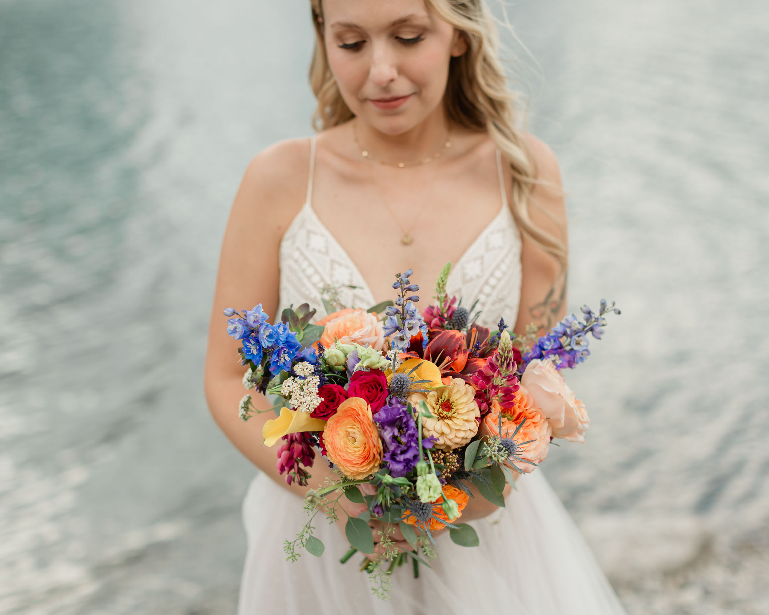 the bride is laughing smiling during her portrait in front of the alpine lake and mountain views