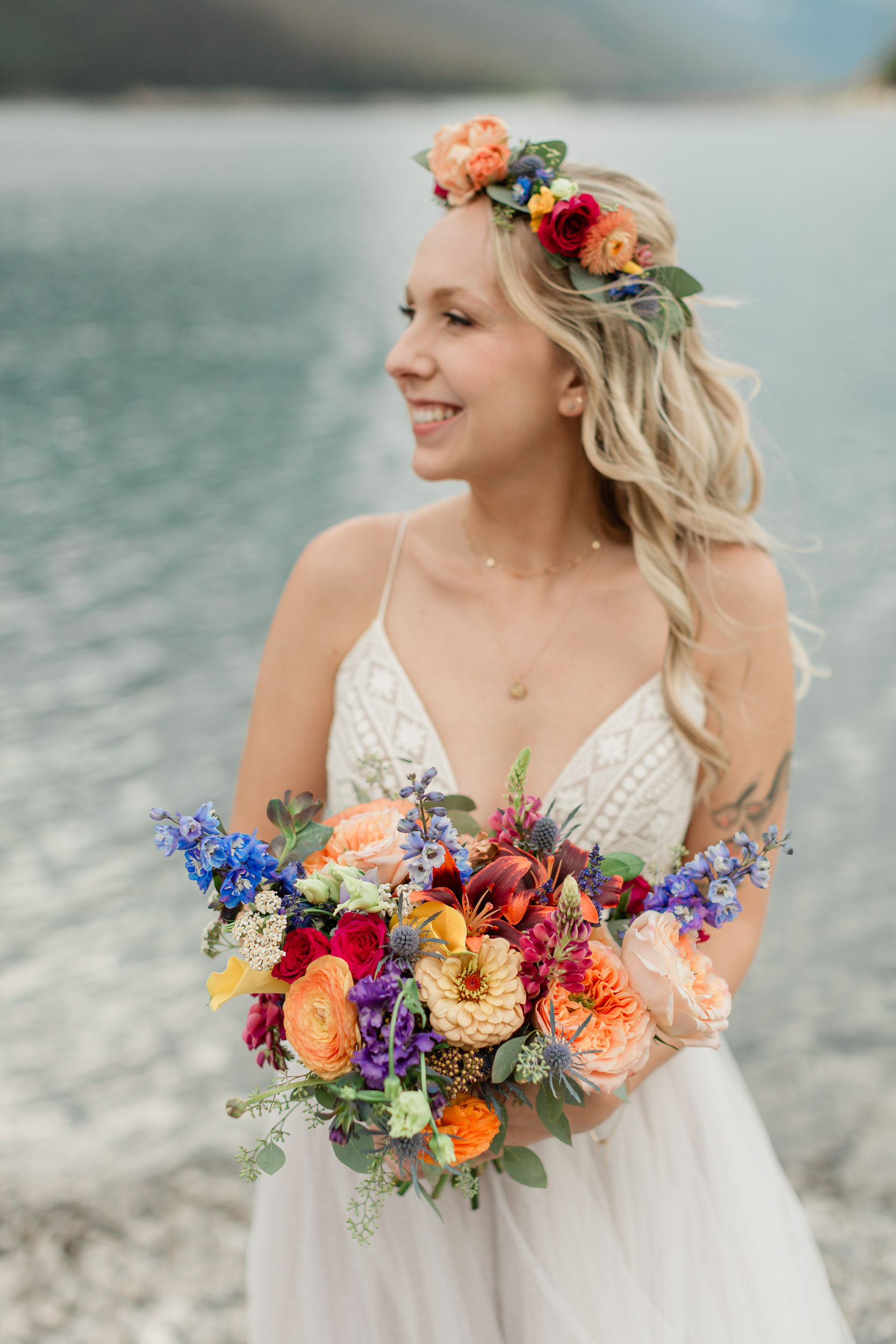 the bride is laughing smiling during her portrait in front of the alpine lake and mountain views