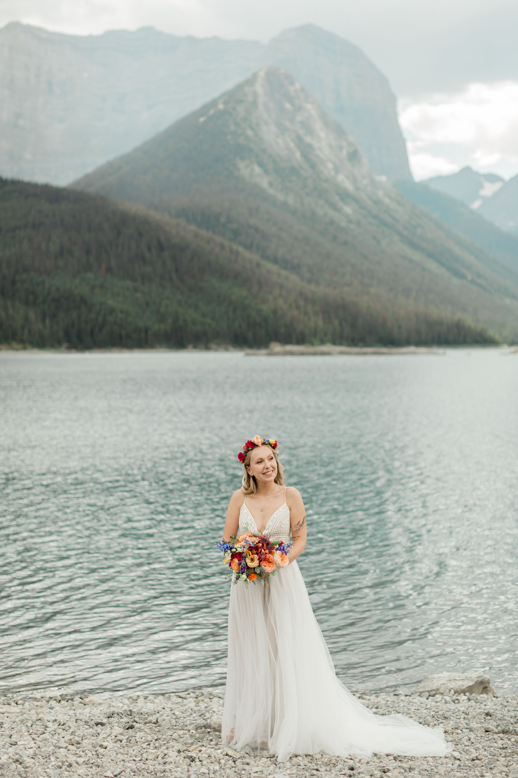 the bride is laughing smiling during her portrait in front of the alpine lake and mountain views