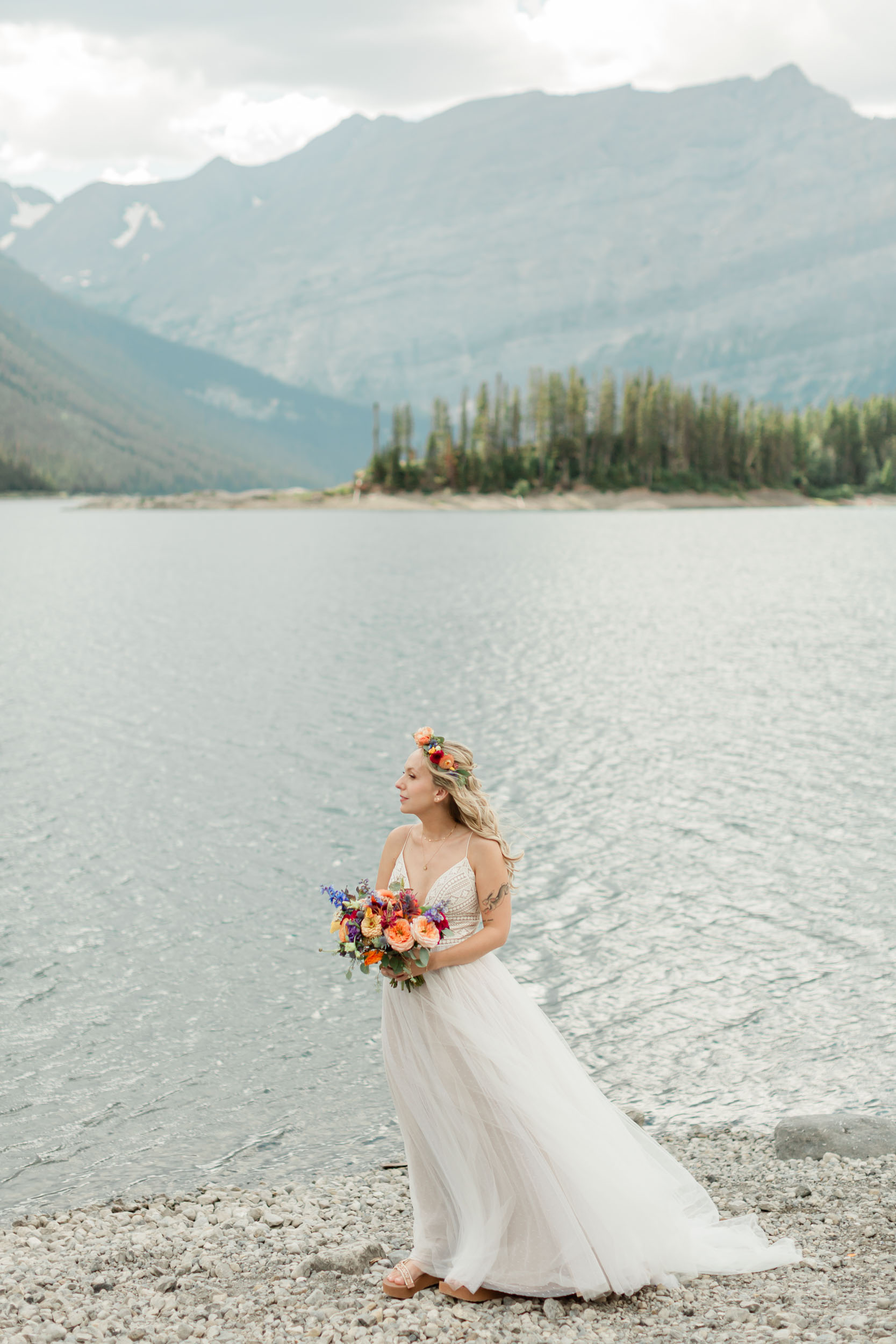 the bride is laughing smiling during her portrait in front of the alpine lake and mountain views