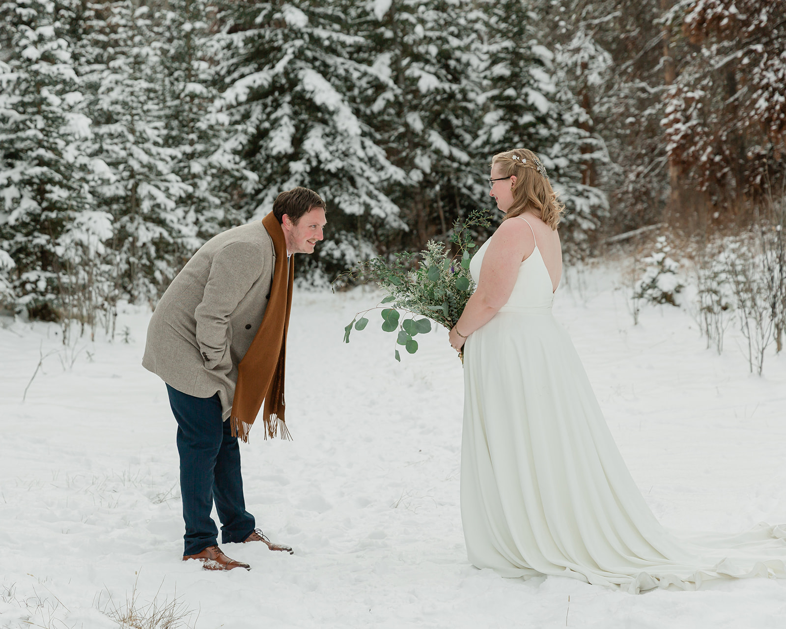 Couple laughing during their snowy first look at their Banff winter elopement in Banff National Park.