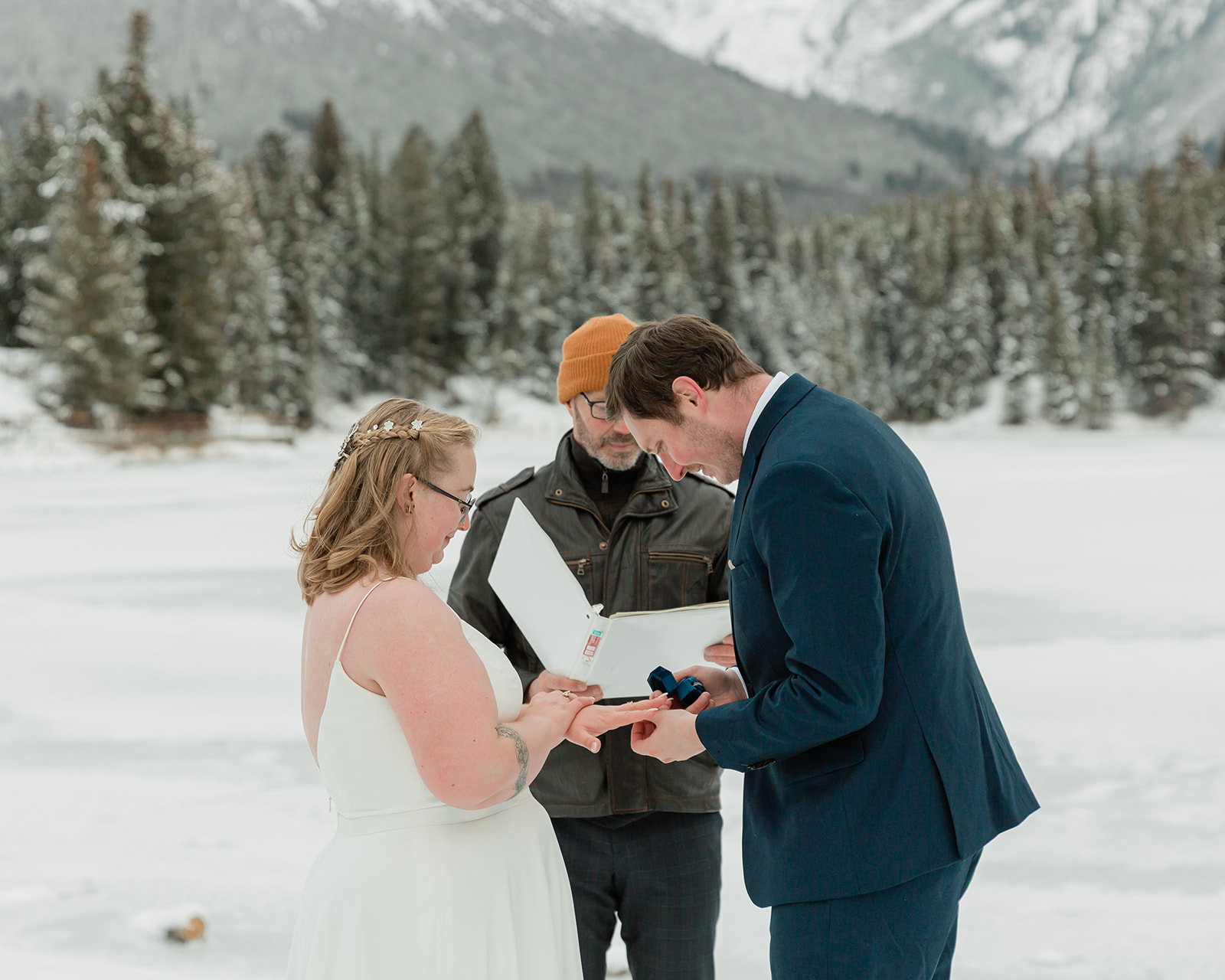 Couple exchanging wedding rings during their snowy Banff winter elopement ceremony in Banff National Park.
