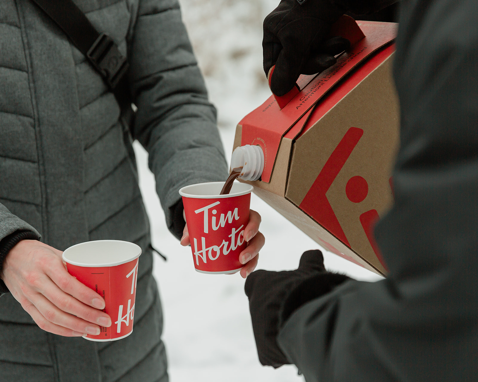 Hot chocolate being poured into Tim Hortons cups for guests during a snowy Banff winter elopement celebration.