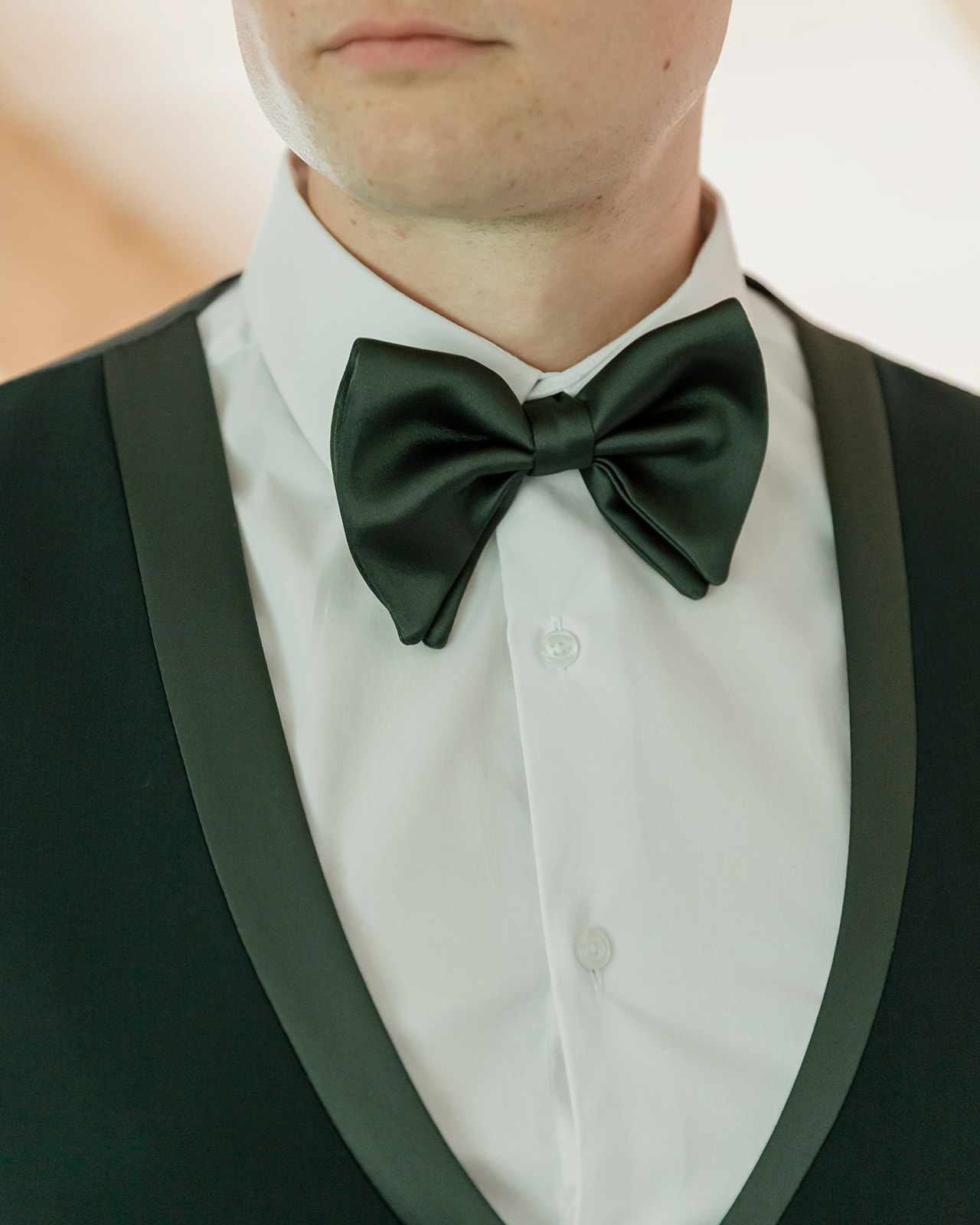 Close-up of a groom’s black bow tie and dark green suit while getting ready for a Moraine Lake elopement in Banff National Park.