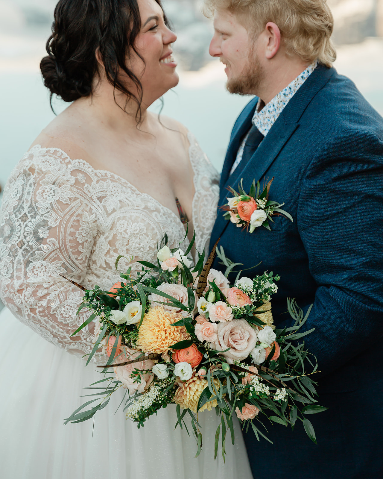 Close-up of Rachel and Russell smiling together during their Banff elopement, with Rachel holding a colorful peach, cream, and greenery bridal bouquet.